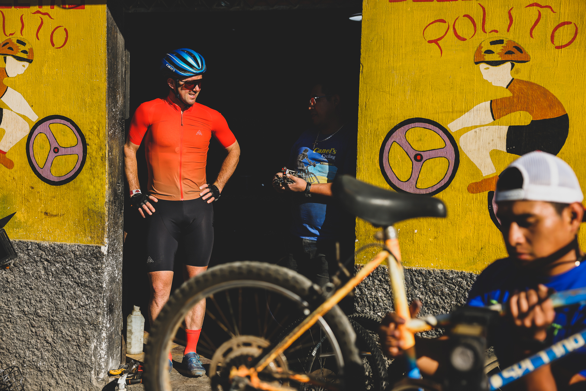Rider standing in a bike shop doorway painted with cyclists and wheels