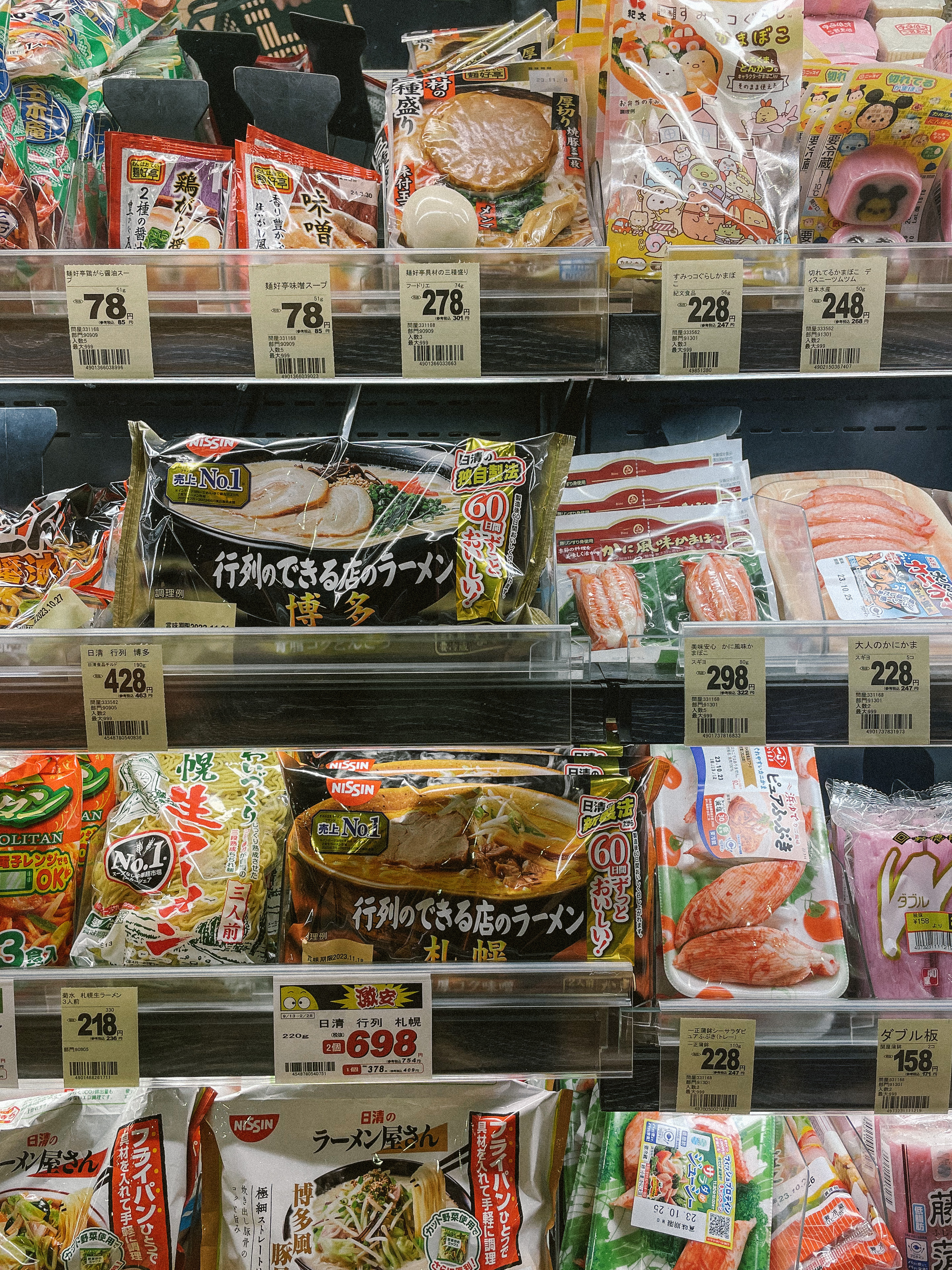 Packaged ramen and surimi on a chilled convenience store shelf with price tags