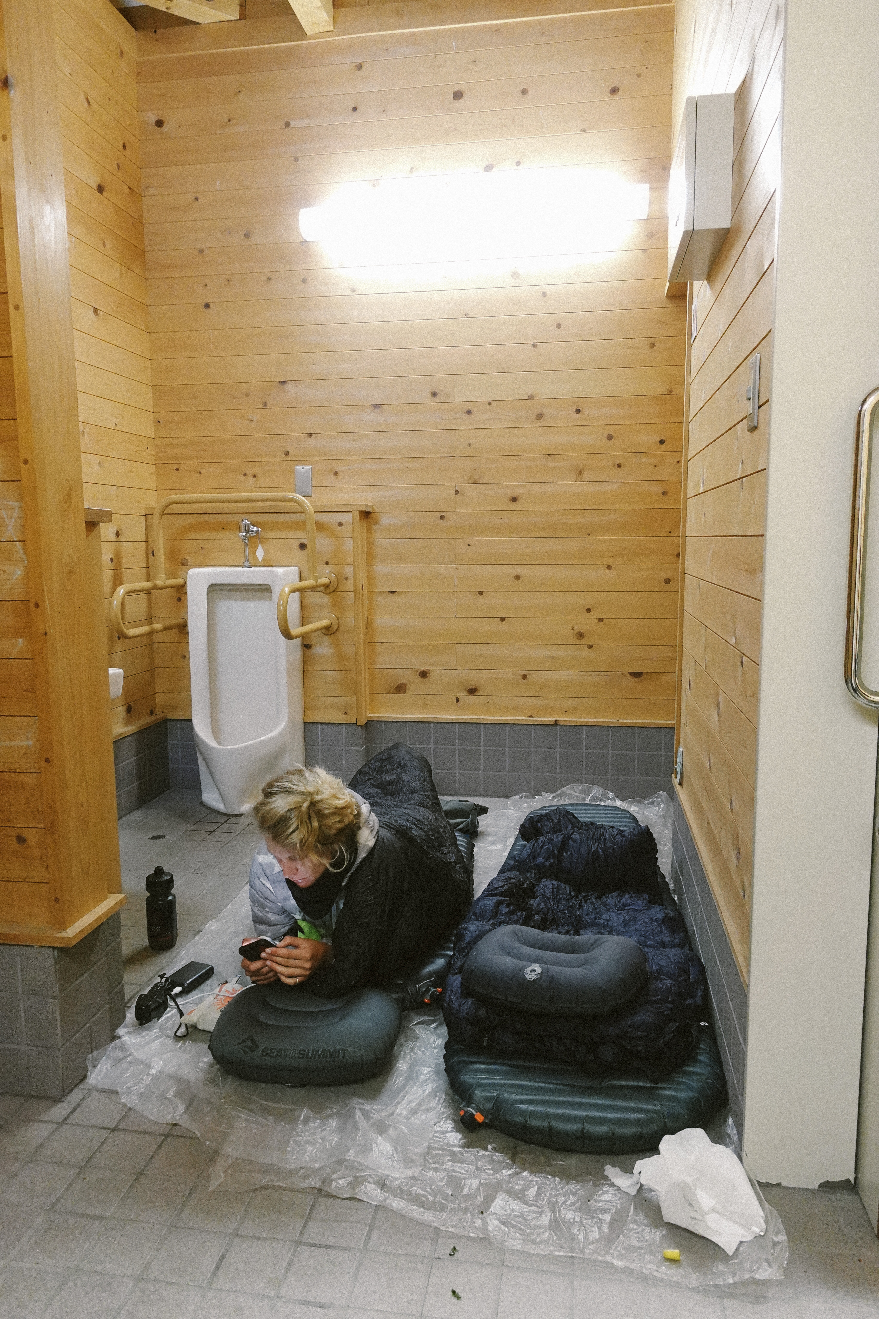 Rider on sleeping mats laid out on the floor of a public toilet block