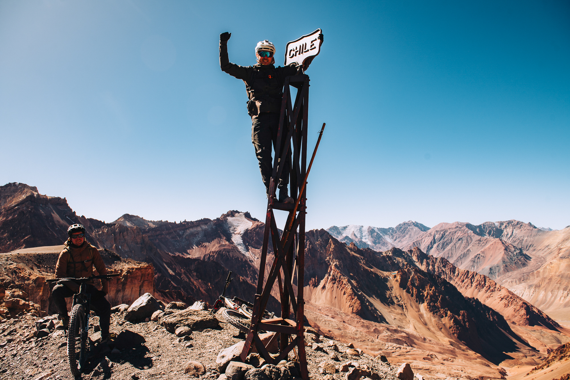 Rider standing on a metal tower holding a sign reading Chile