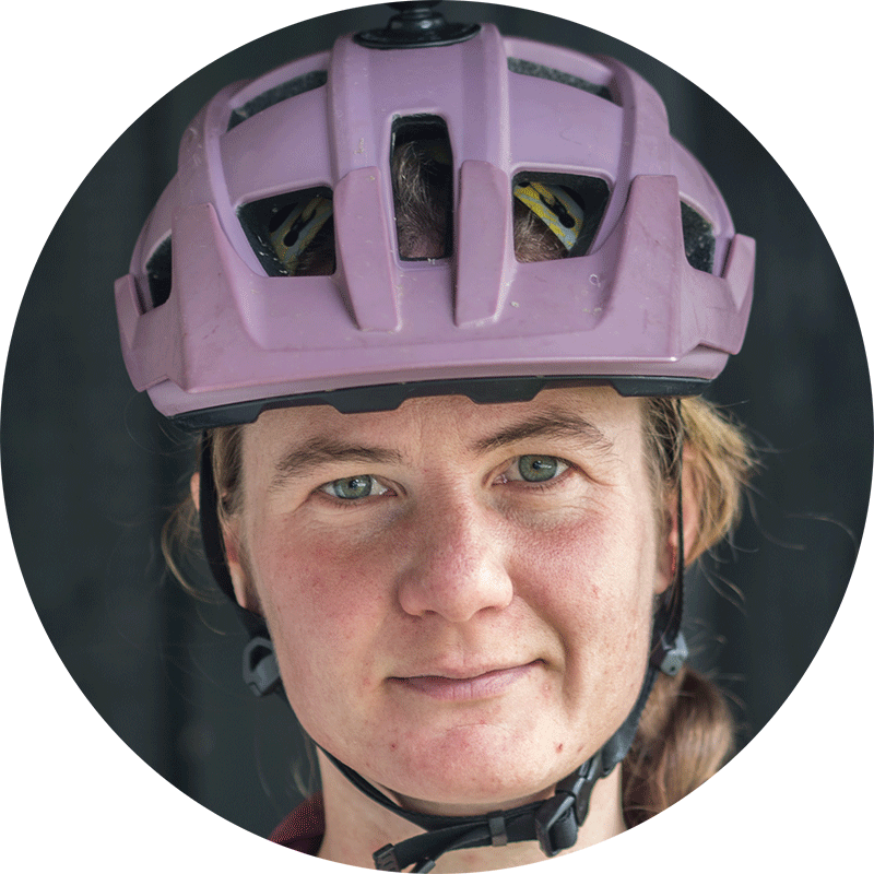 Annie Evans in a mauve mountain bike helmet against a dark background
