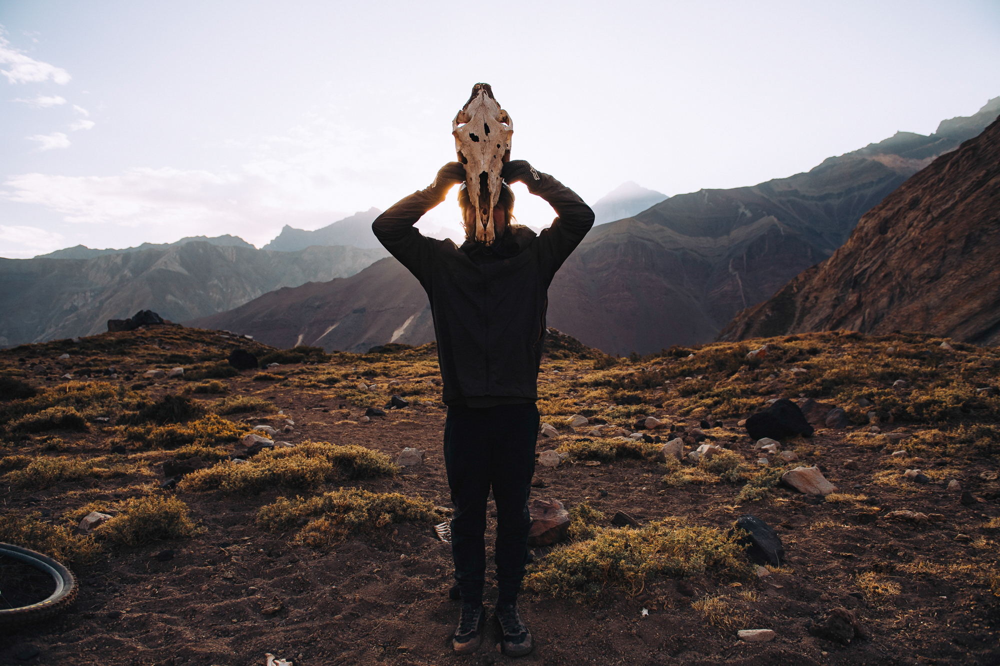 Rider holding an animal skull over their head against the mountains