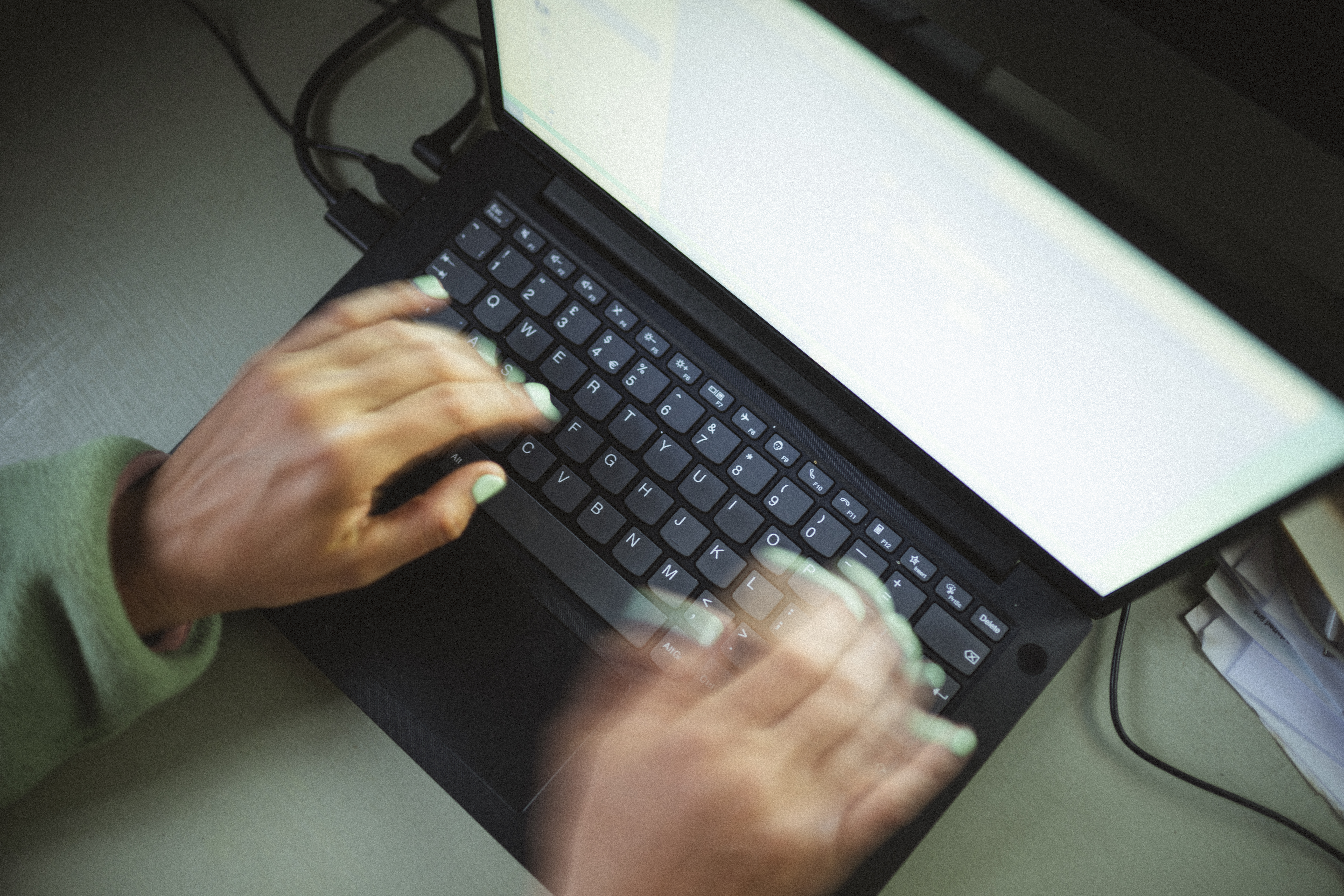 Overhead view of hands typing on a laptop keyboard