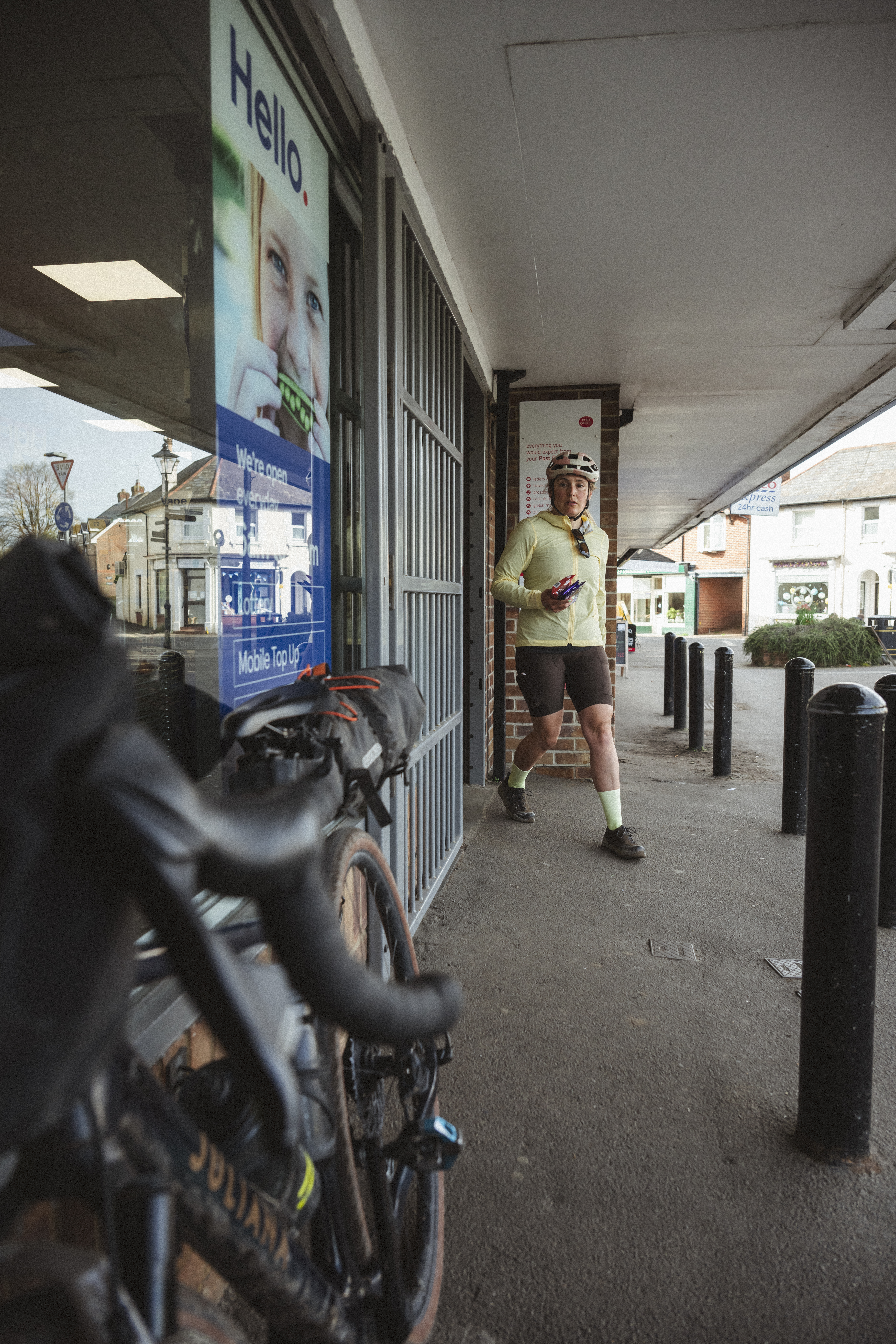 Rider carrying snacks out of a village shop past her loaded bike