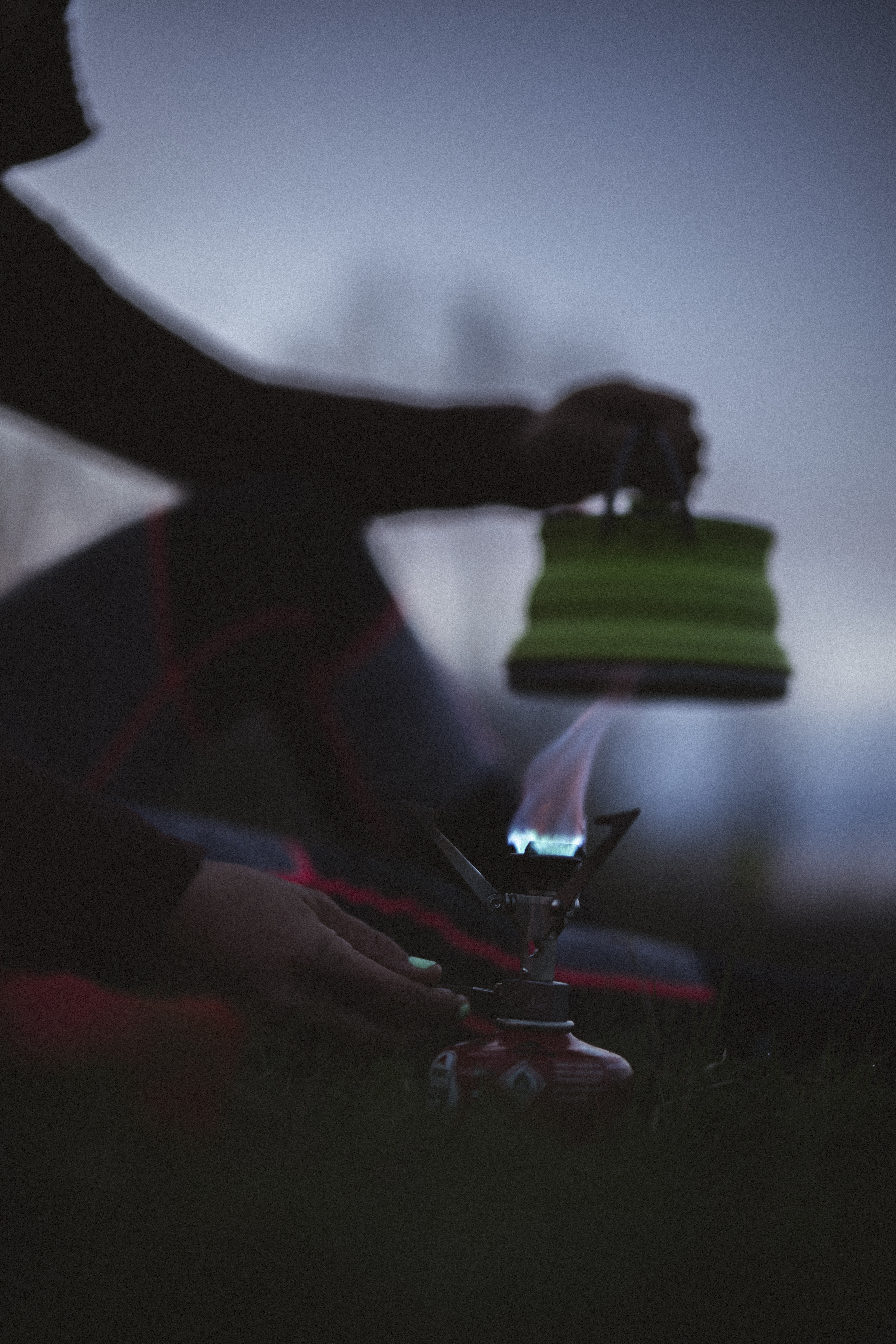Hand holding a pouch of food over a lit camping stove