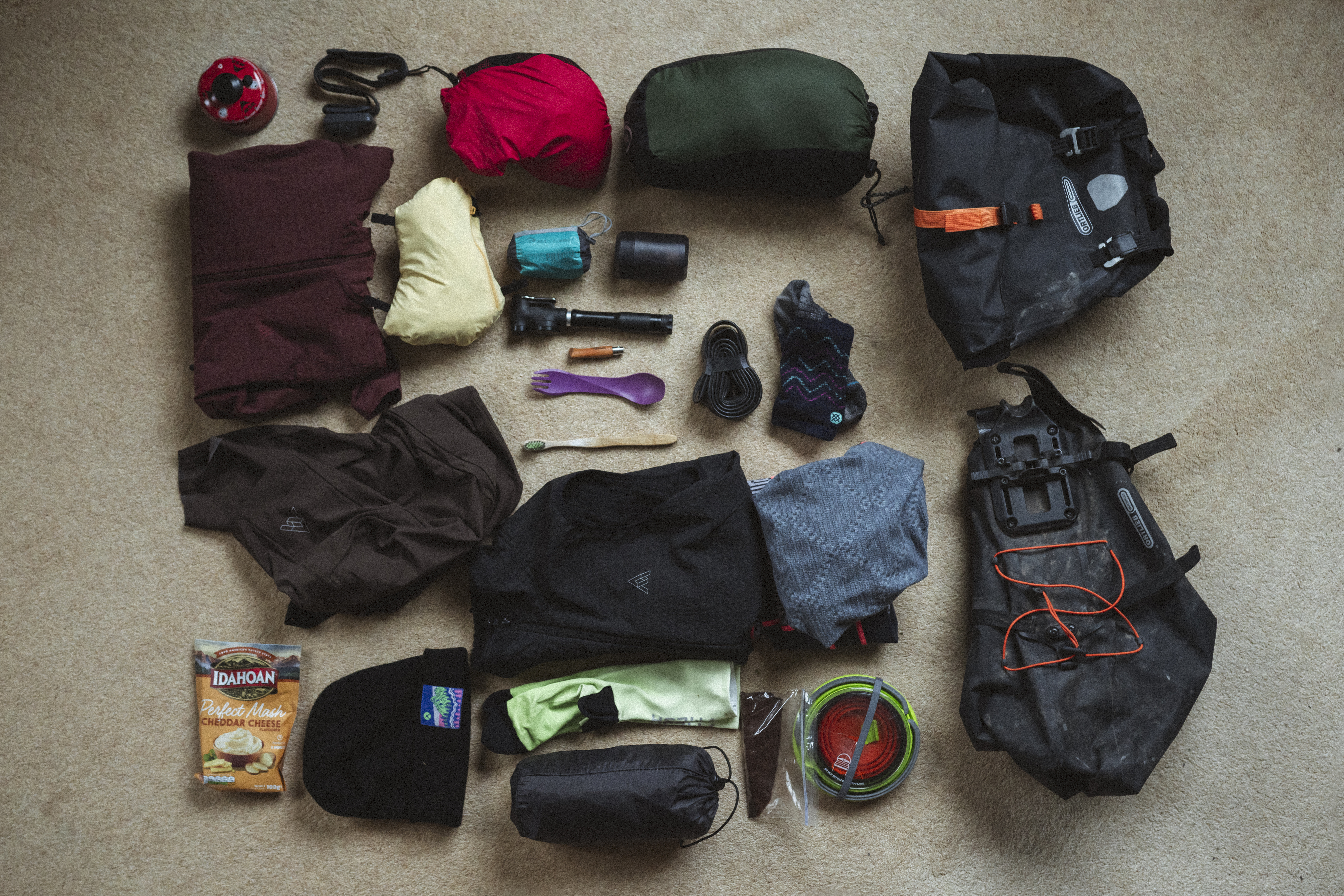 Overnight kit laid out in a grid: sleeping bag, stove, layers and bike bags