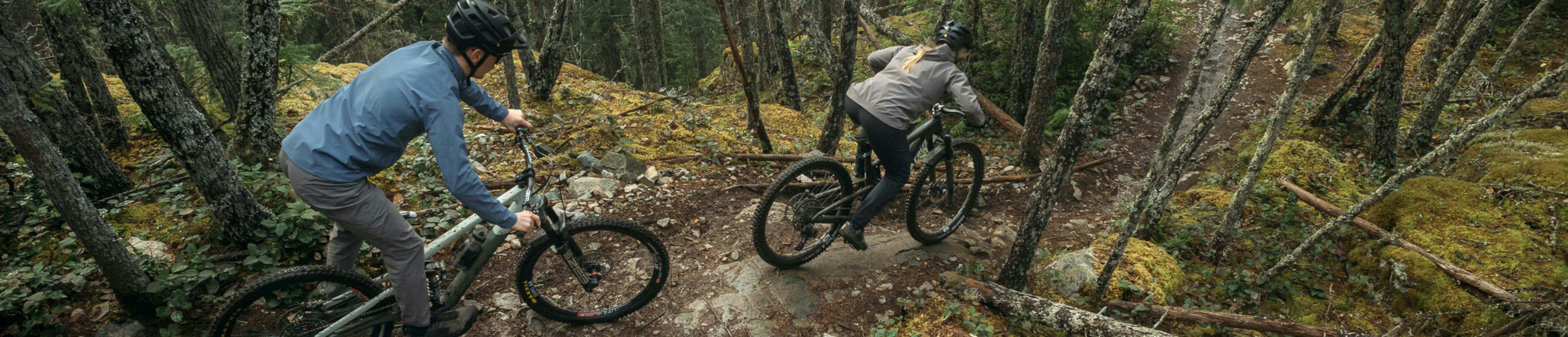 Two people riding down a steep rock covered in grass