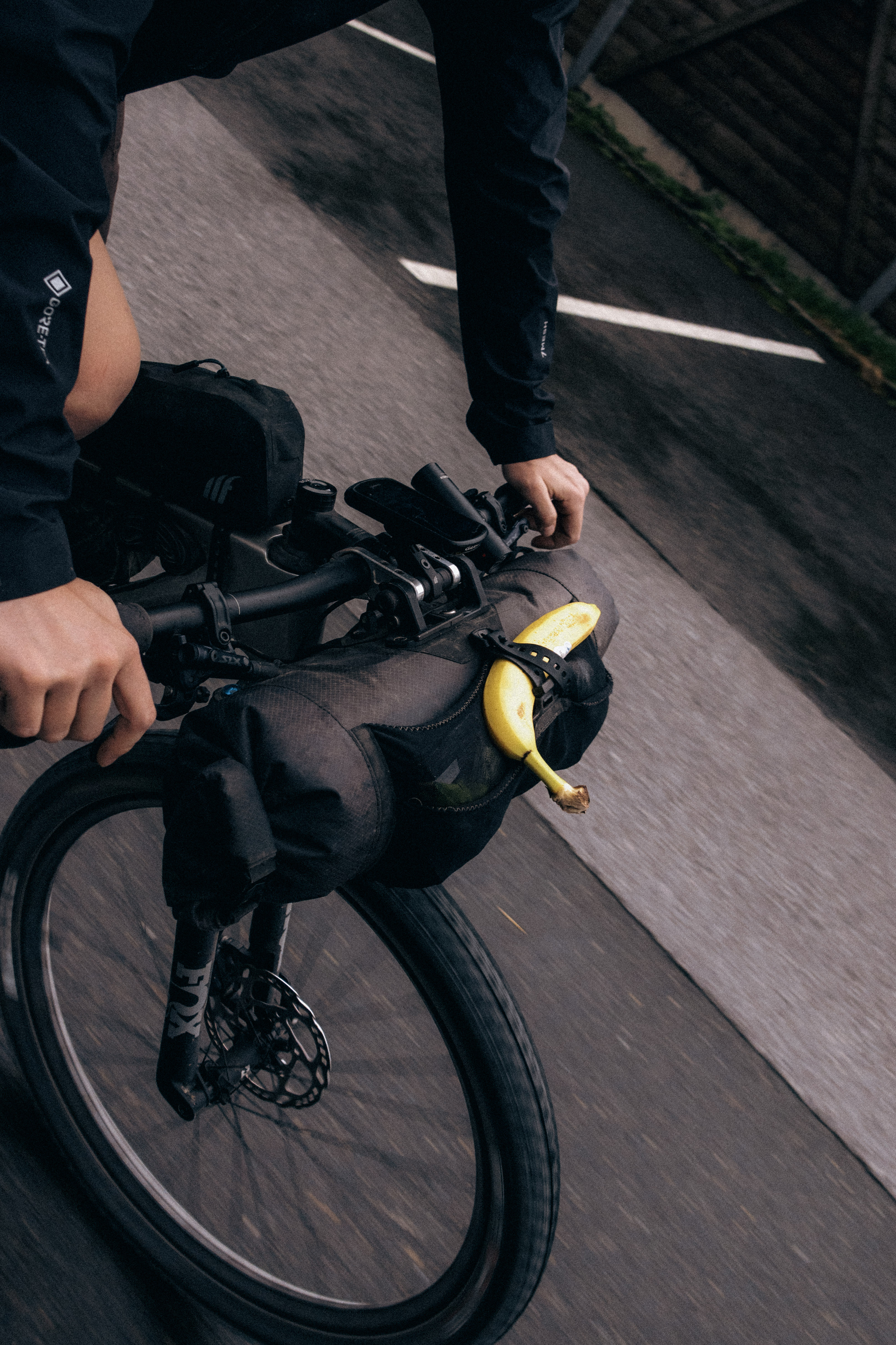 Close view of handlebars and a black bar bag with a half-peeled banana tucked into the strap