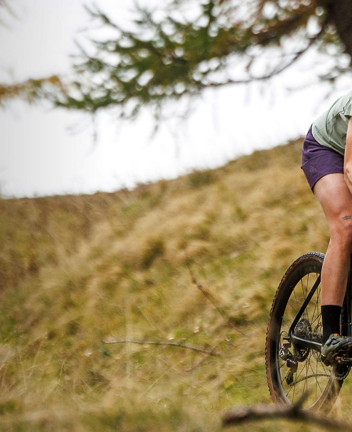 Woman riding a gravel bike wearing a helmet and 7mesh merino shirt