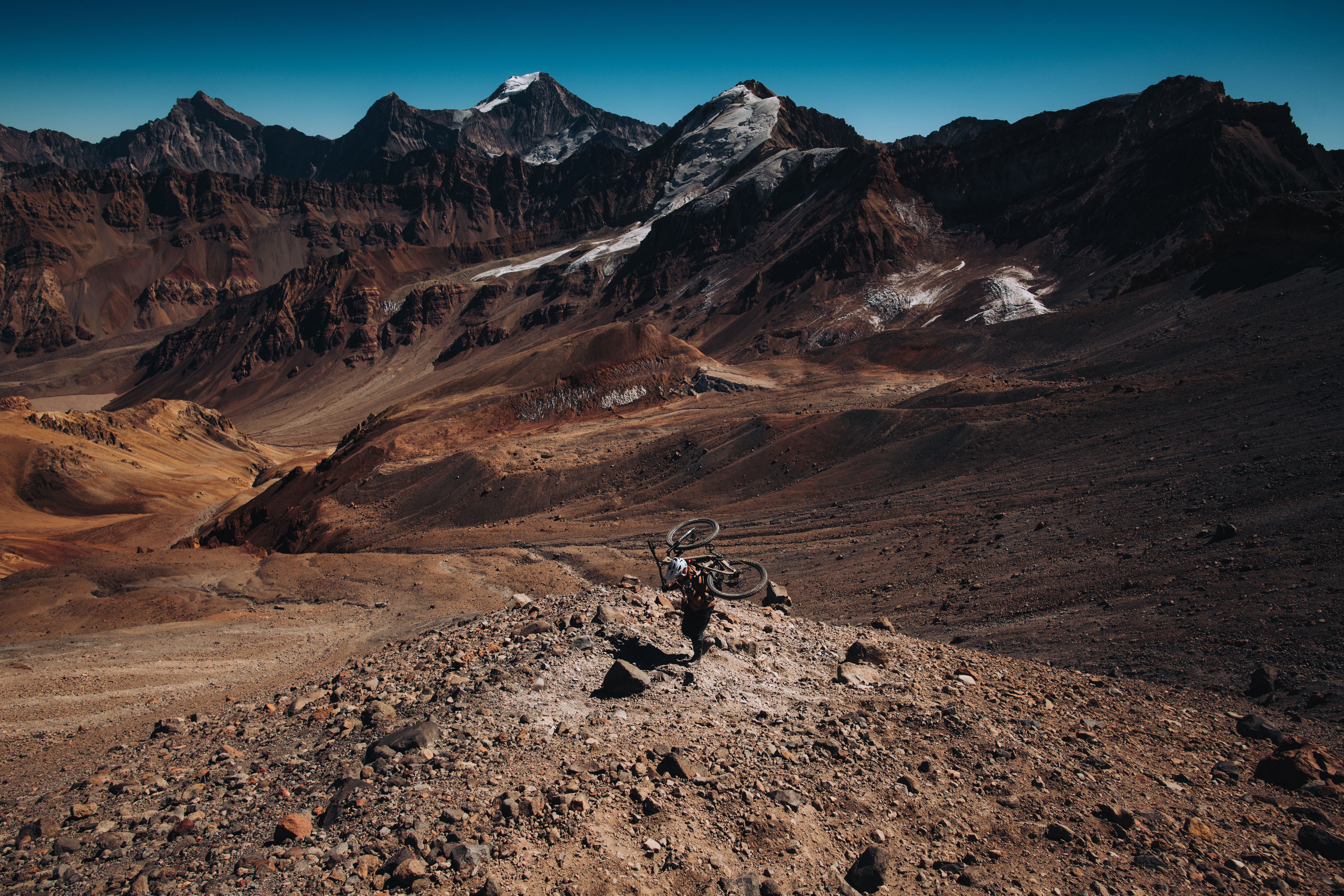Loaded mountain bike parked alone on a broad red-brown scree basin