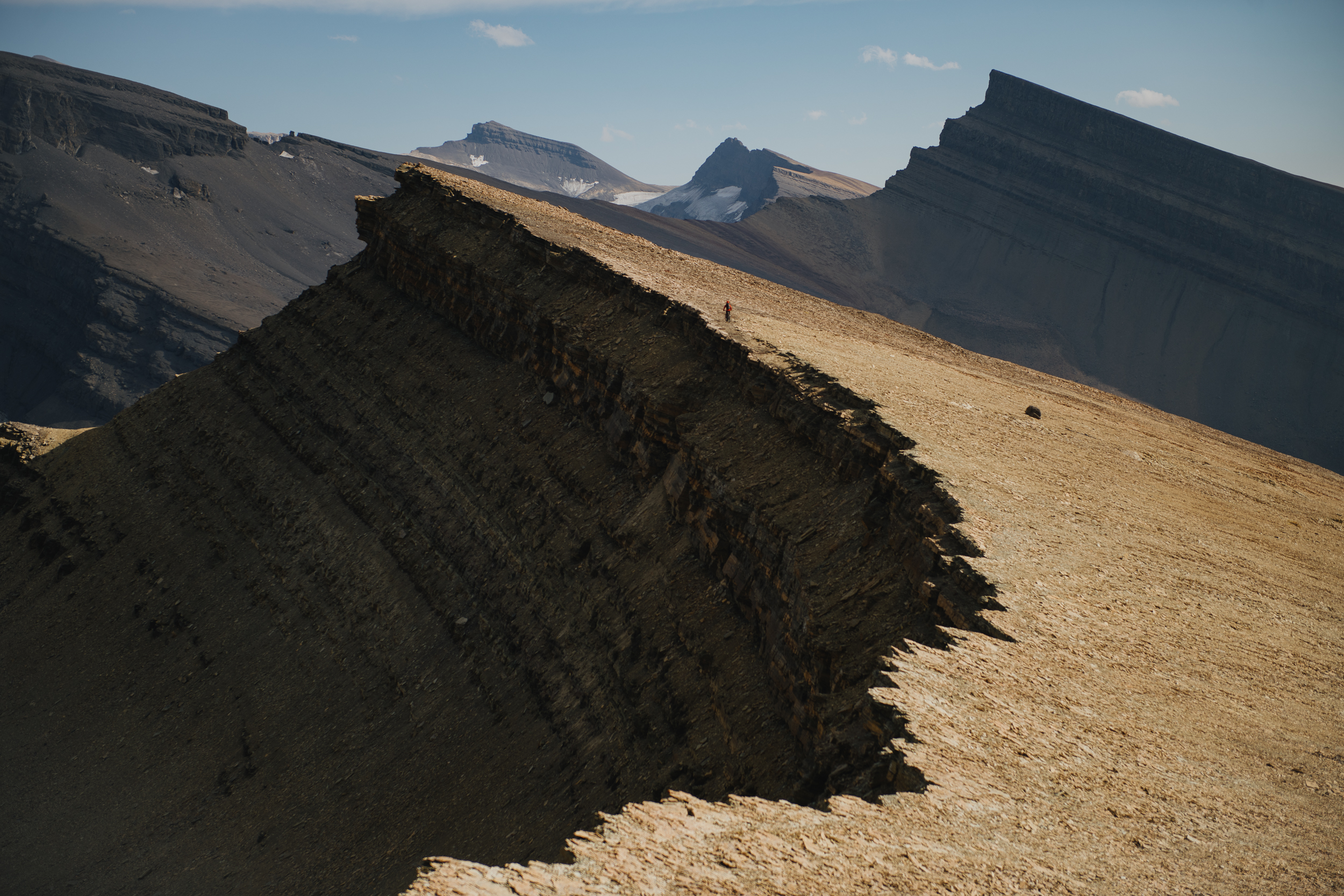 Long sunlit ridge crest dropping away toward layered rock faces