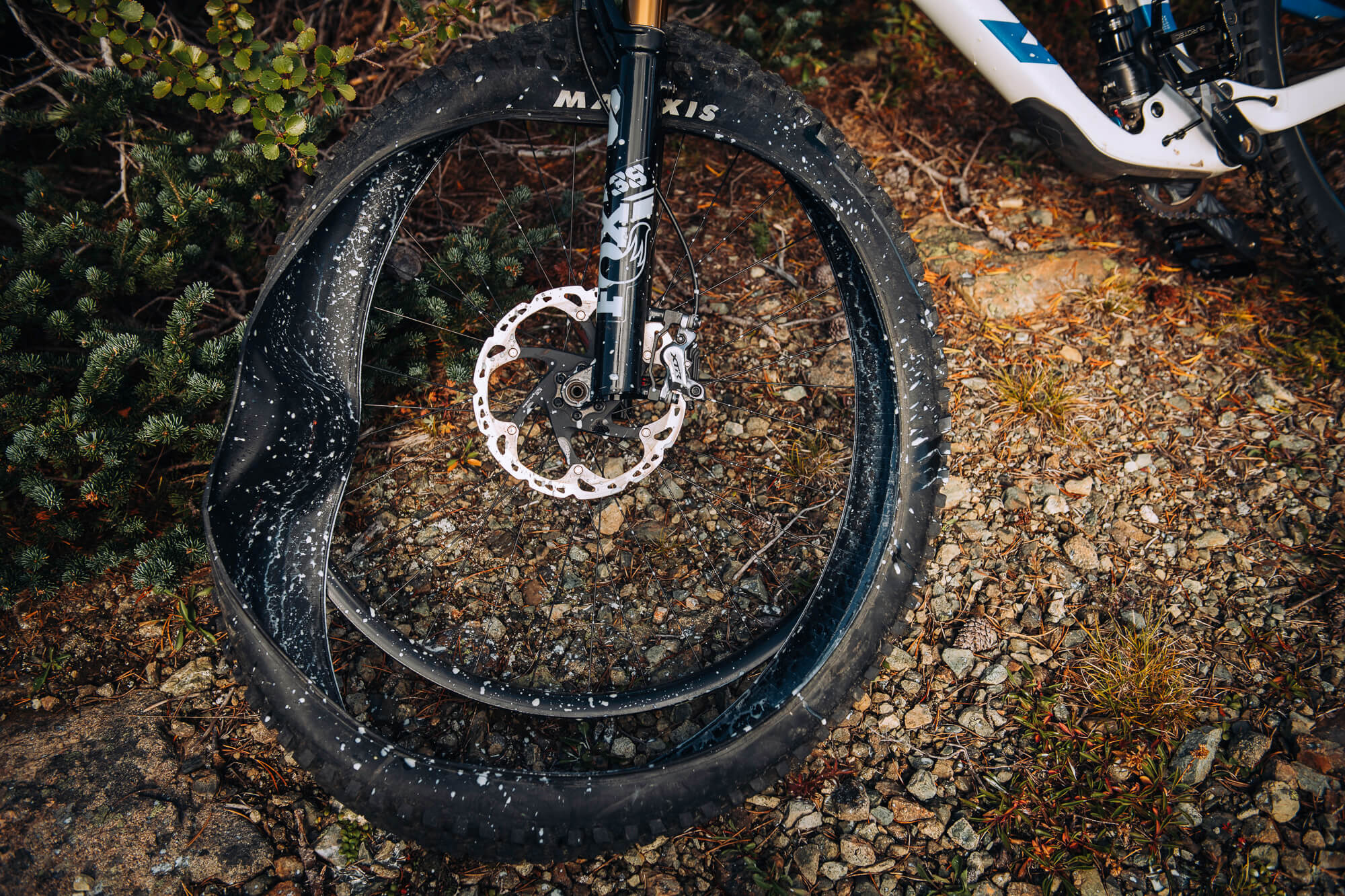 Close view of a mud-spattered front wheel and fork on rocky ground