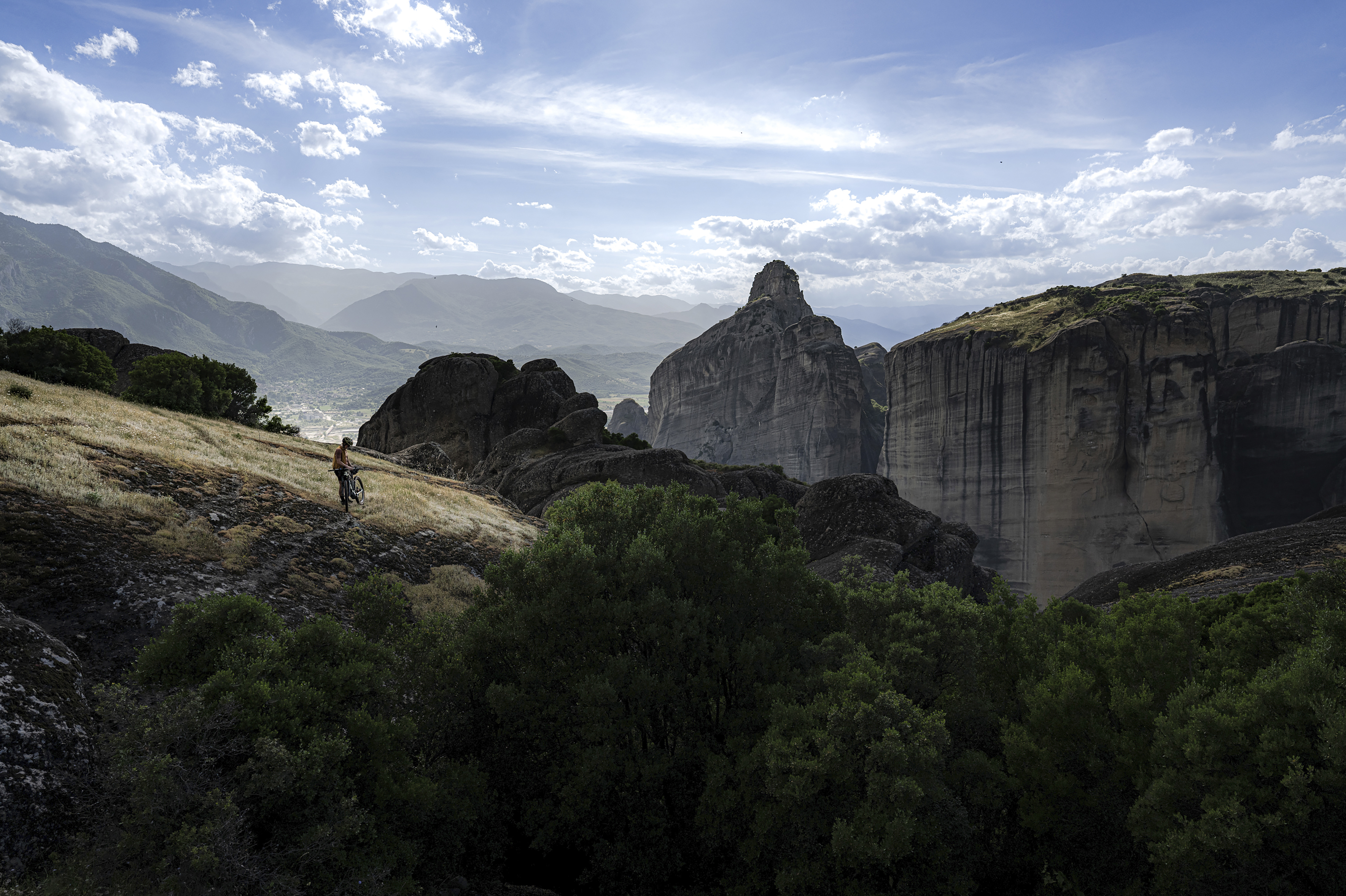 Distant rider on a hillside path above huge sandstone rock towers