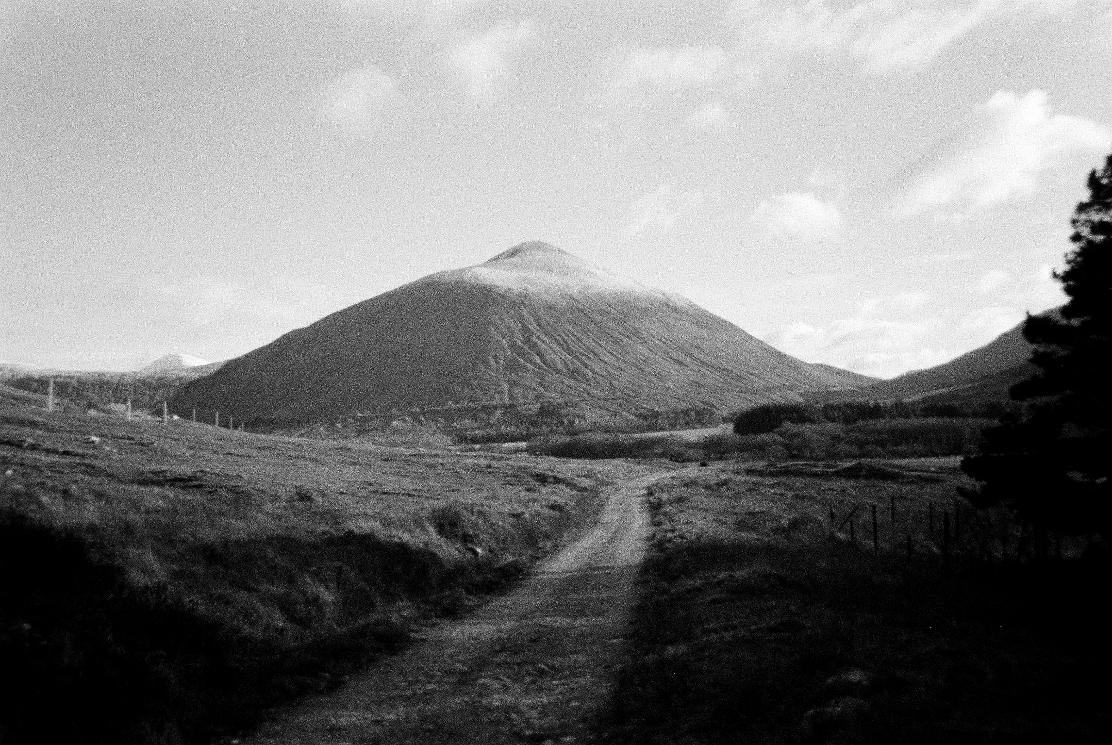 Gravel track leading toward a steep conical hill, black and white