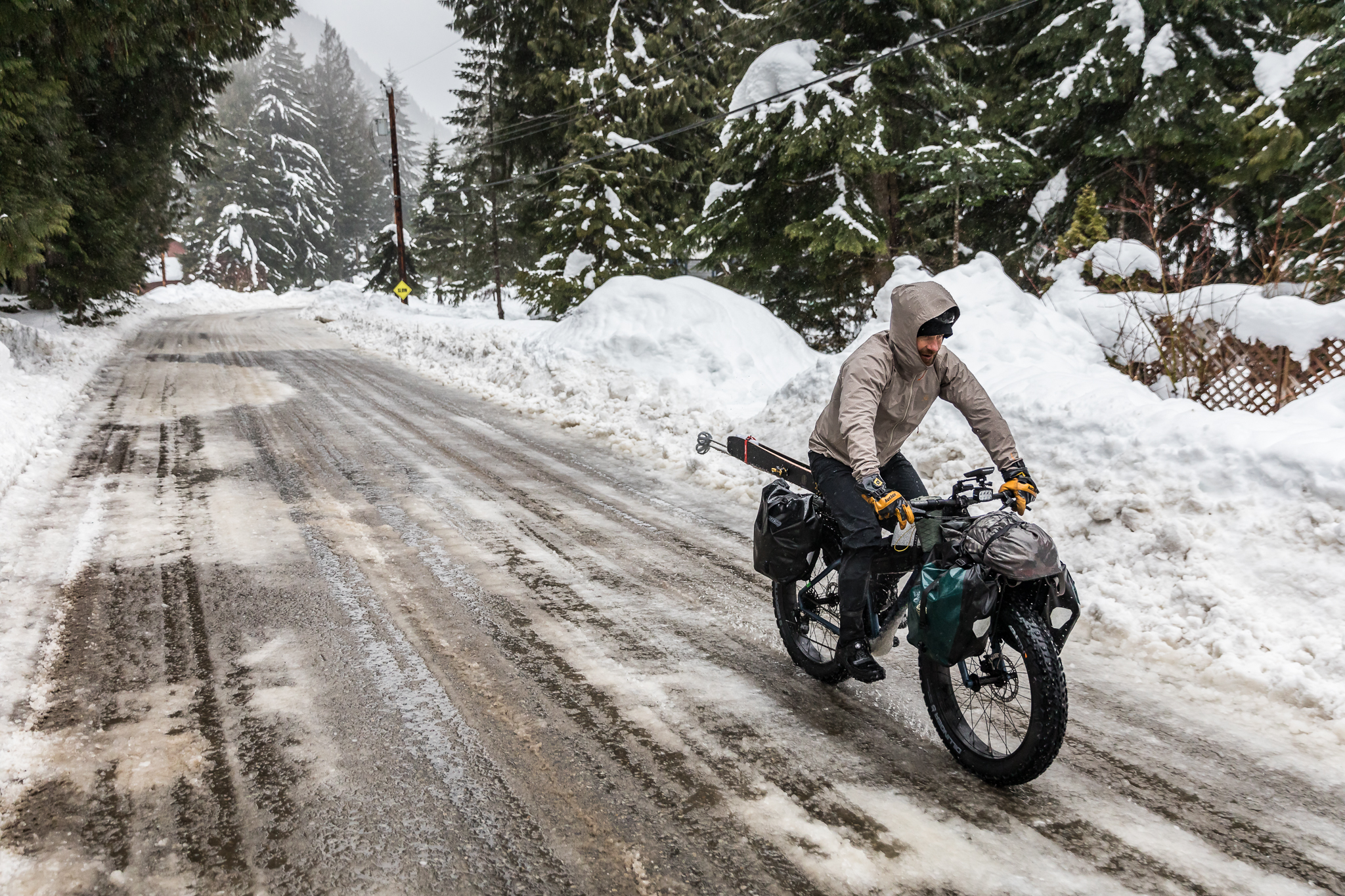 Rider on a loaded fat bike on a slushy road banked with deep snow