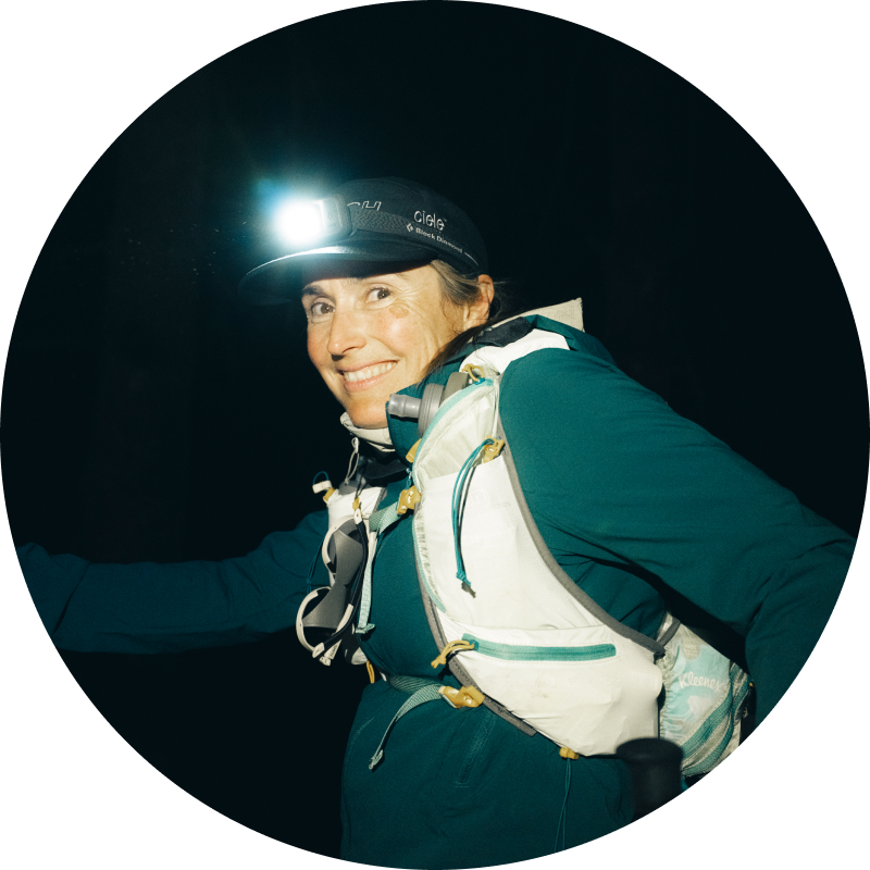 Portrait of Rachael Walker in a head torch and hydration vest at night