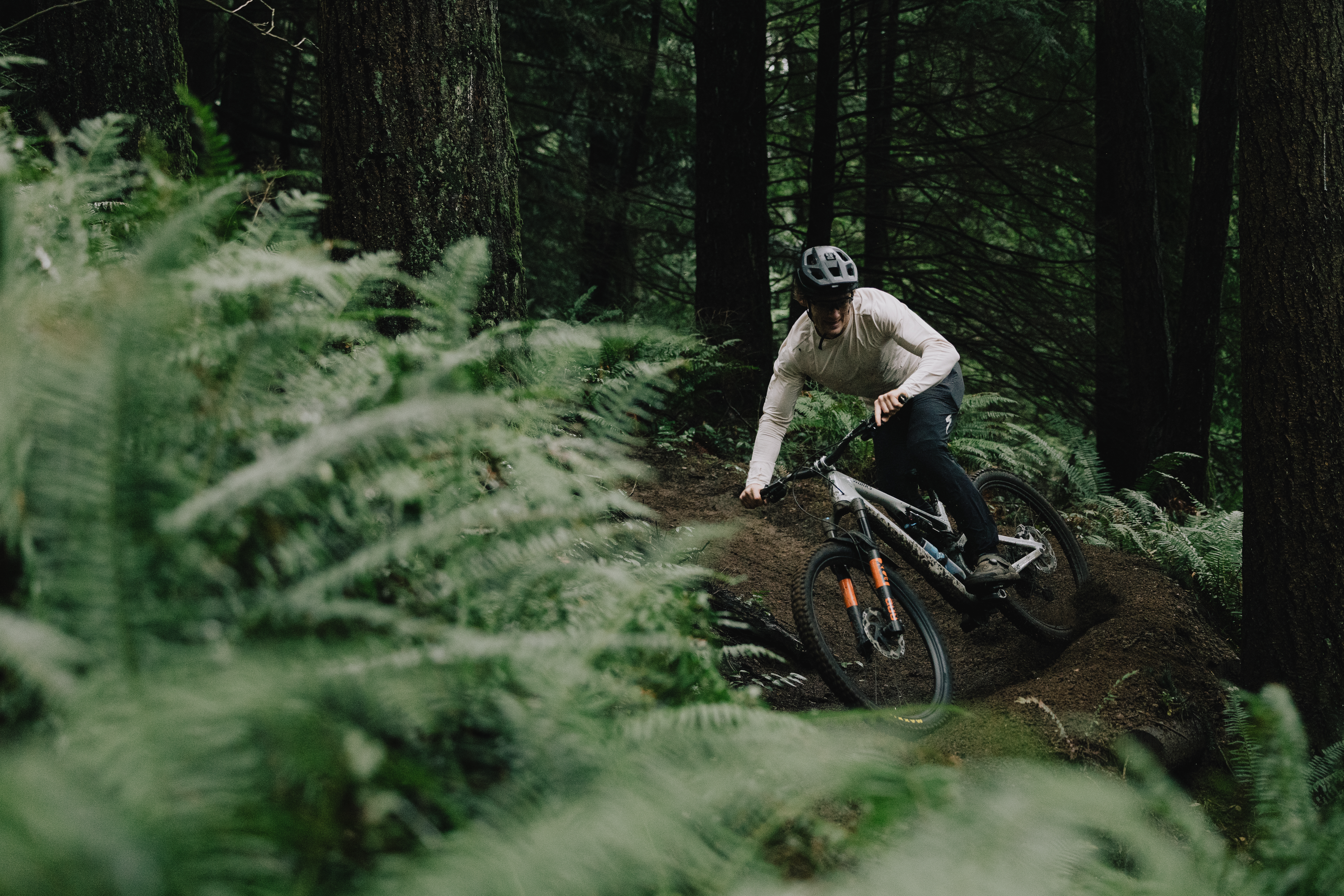 Elliot Jamieson dropping into a fern-lined corner on a dark forest trail