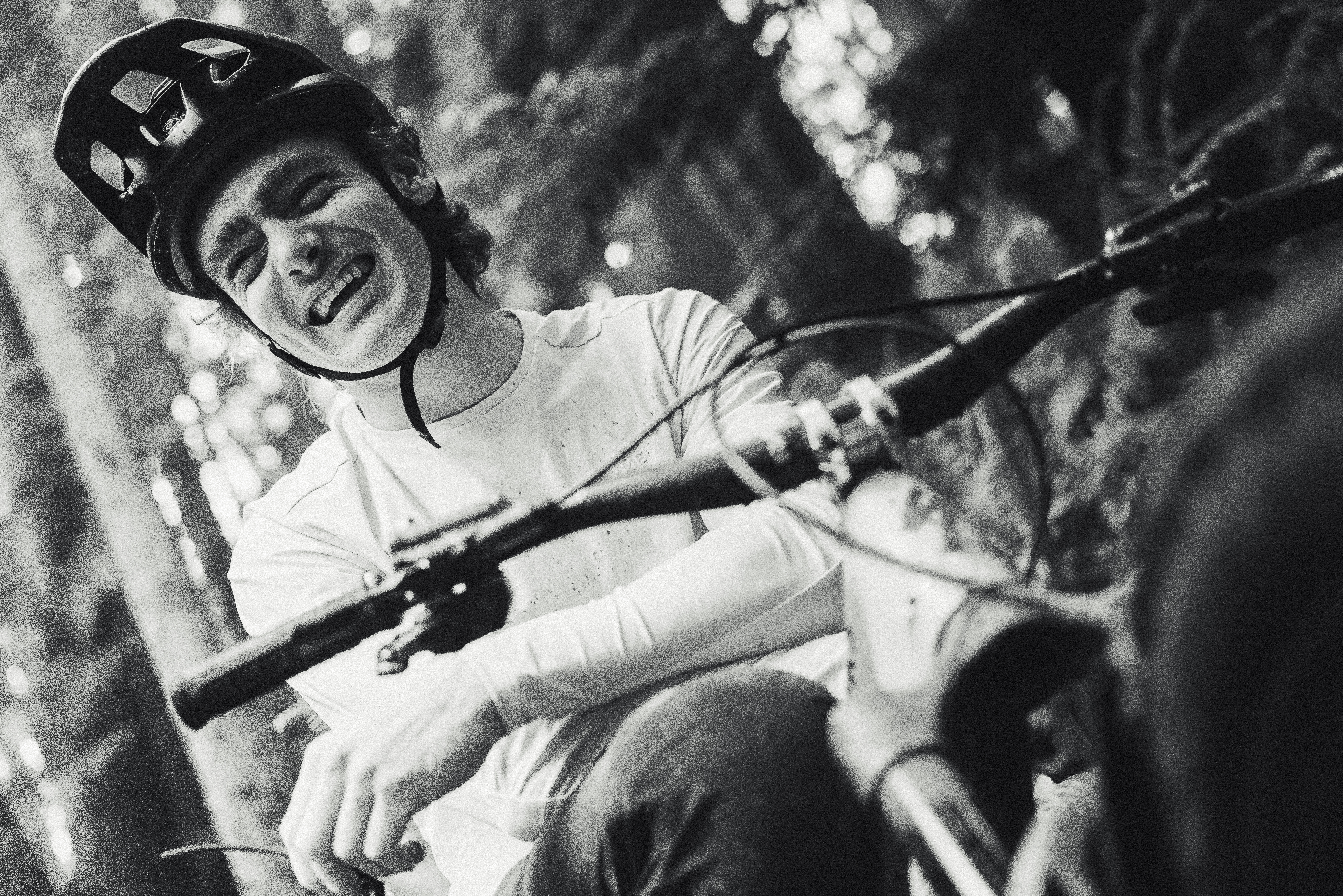 Black and white close-up of Elliot Jamieson laughing over the bars of his bike