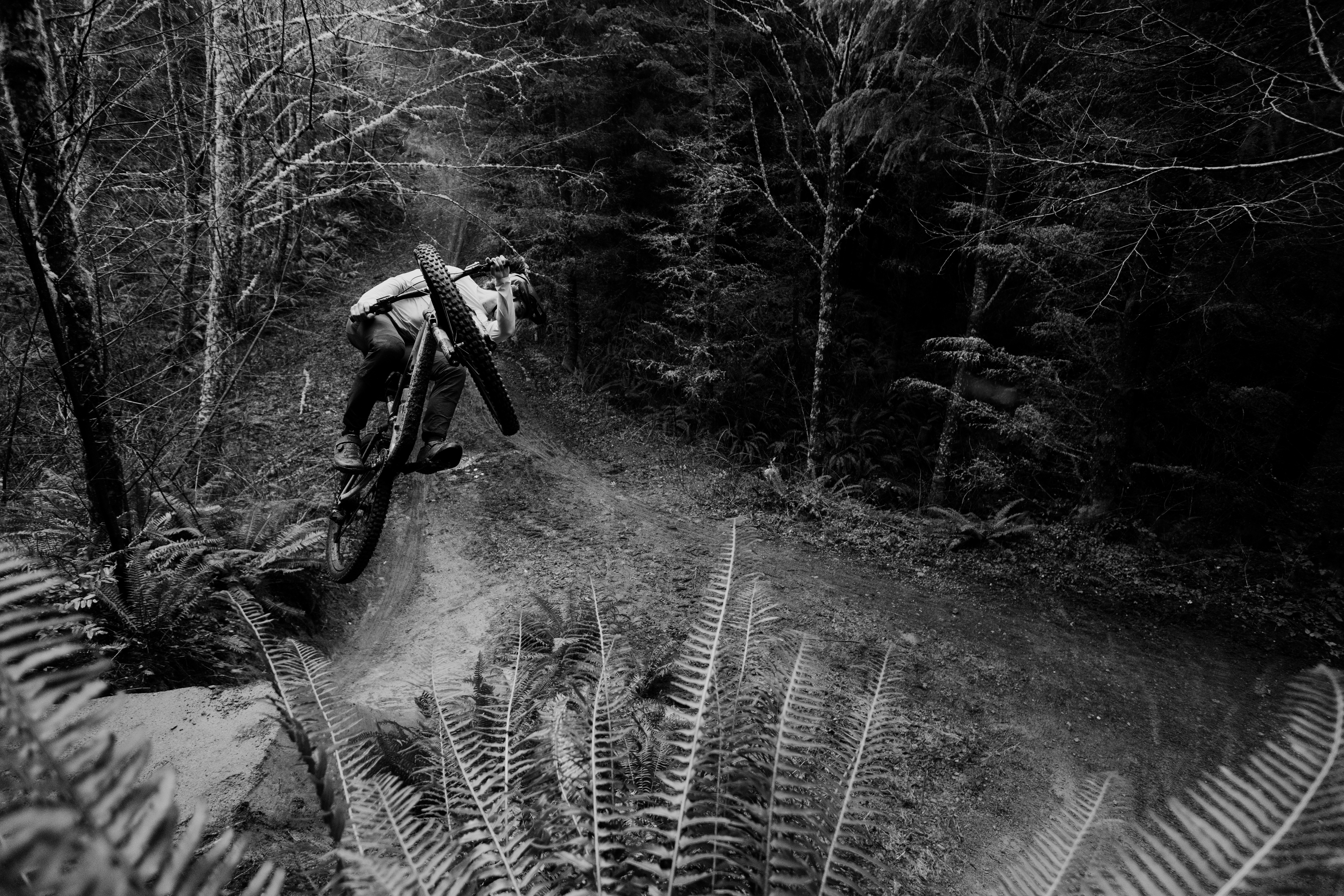 Black and white shot of Elliot Jamieson whipping the bike sideways off a dirt lip