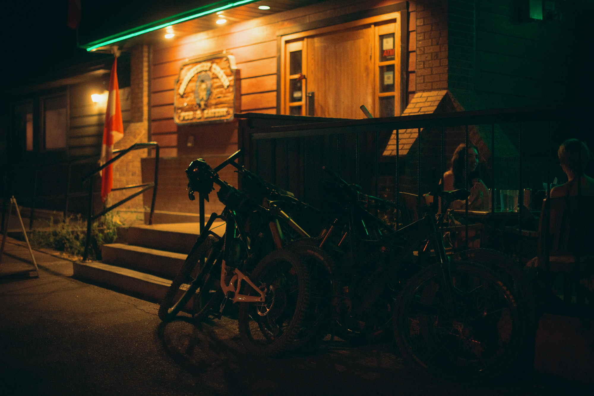 Bikes leaning outside a lit timber building at night