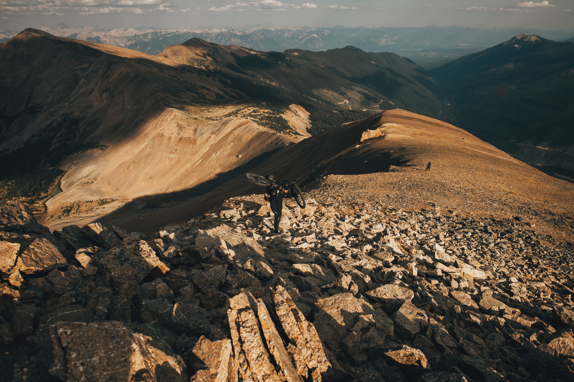 Bike lying on a broad sunlit scree ridge above deep valleys