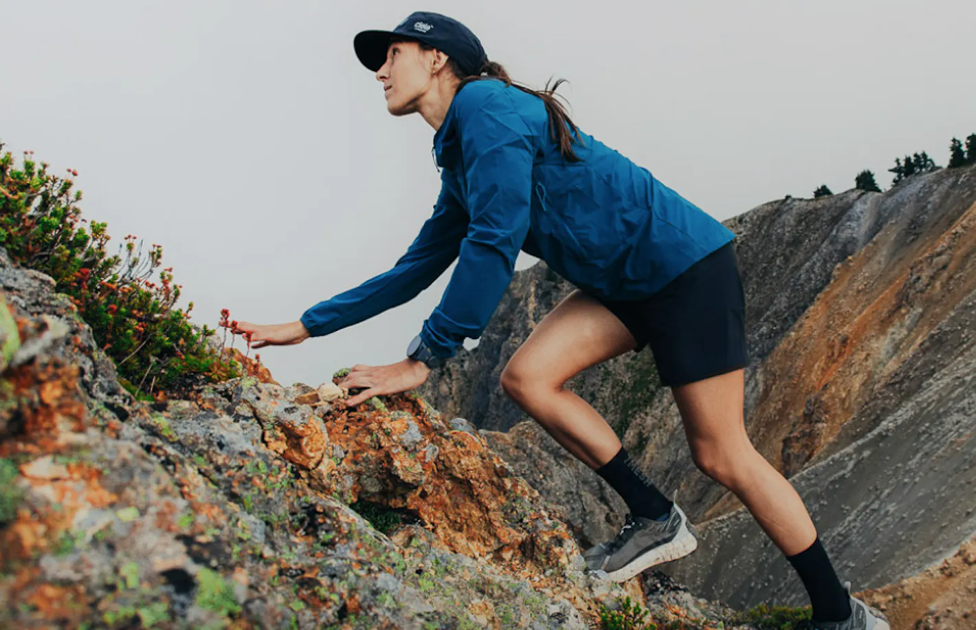 Women in blue jacket climbing a mountain wearing 7mesh shorts