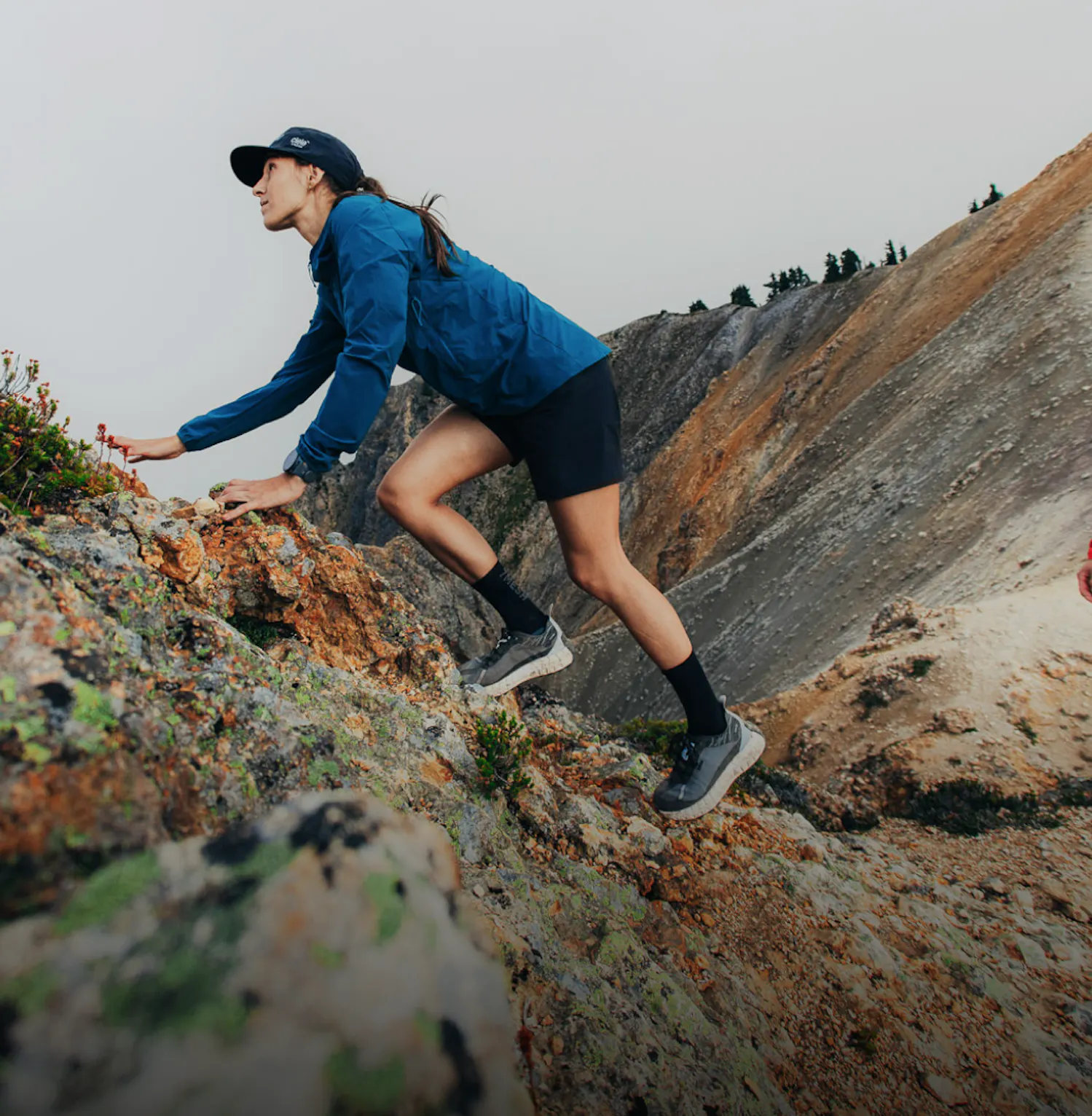 Women in blue jacket climbing a mountain wearing 7mesh shorts