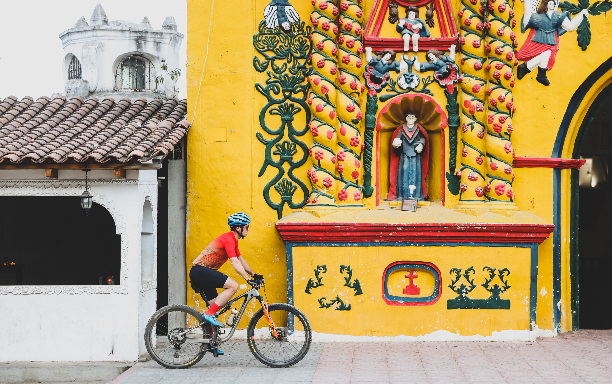 Rider passing a bright yellow church facade covered in painted relief figures