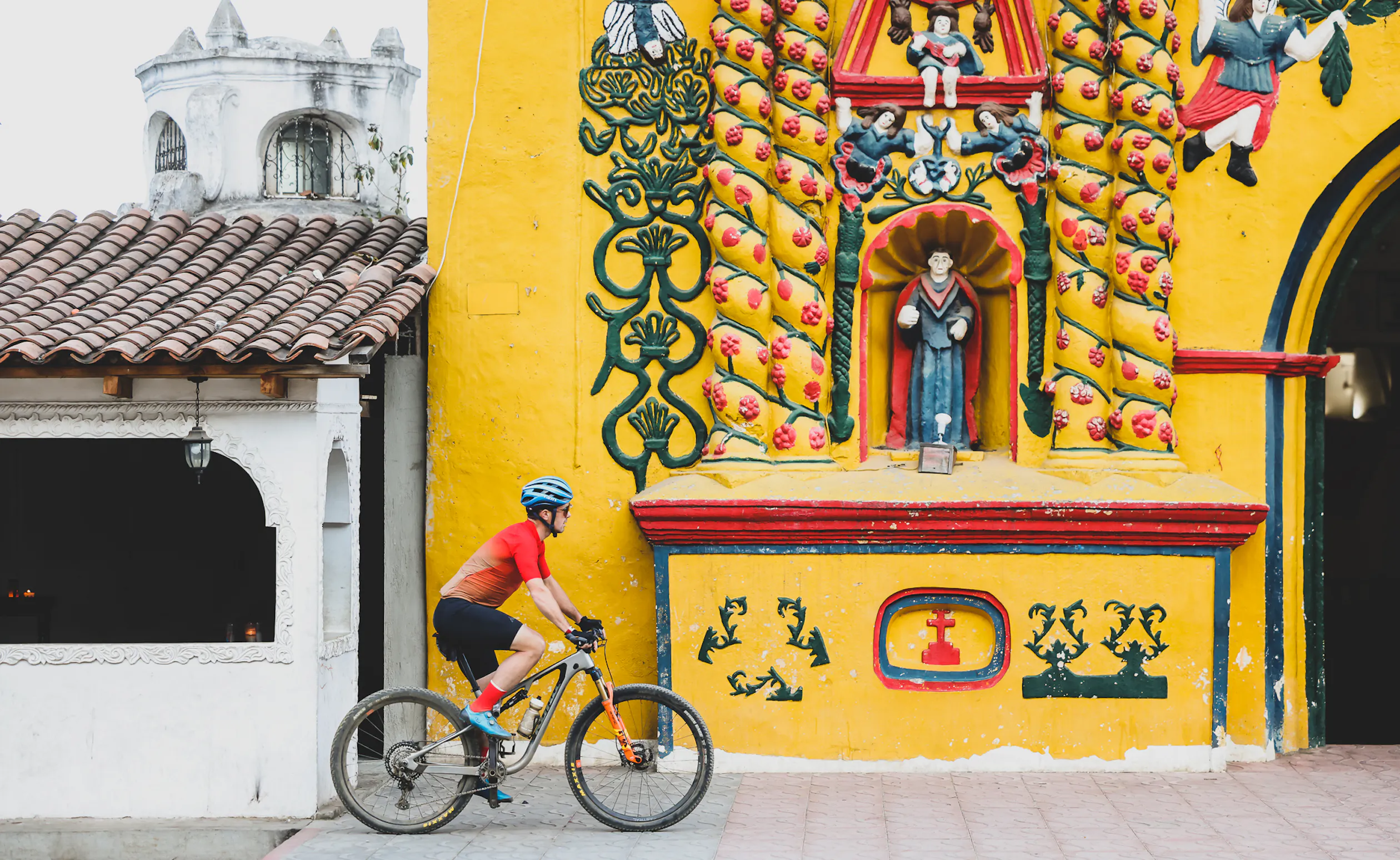 Rider passing a bright yellow church facade covered in painted relief figures