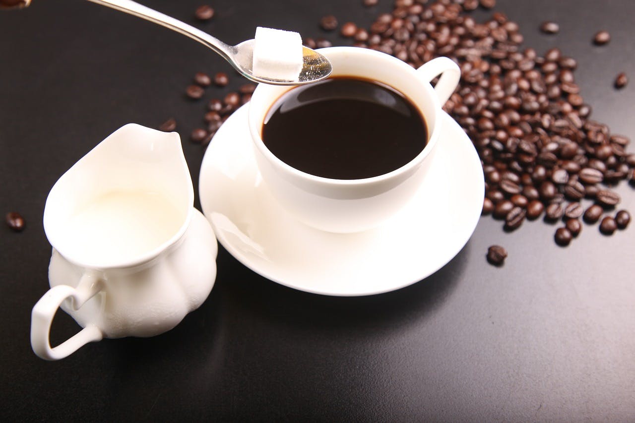 Coffee, sugar cubes, milk and coffee beans