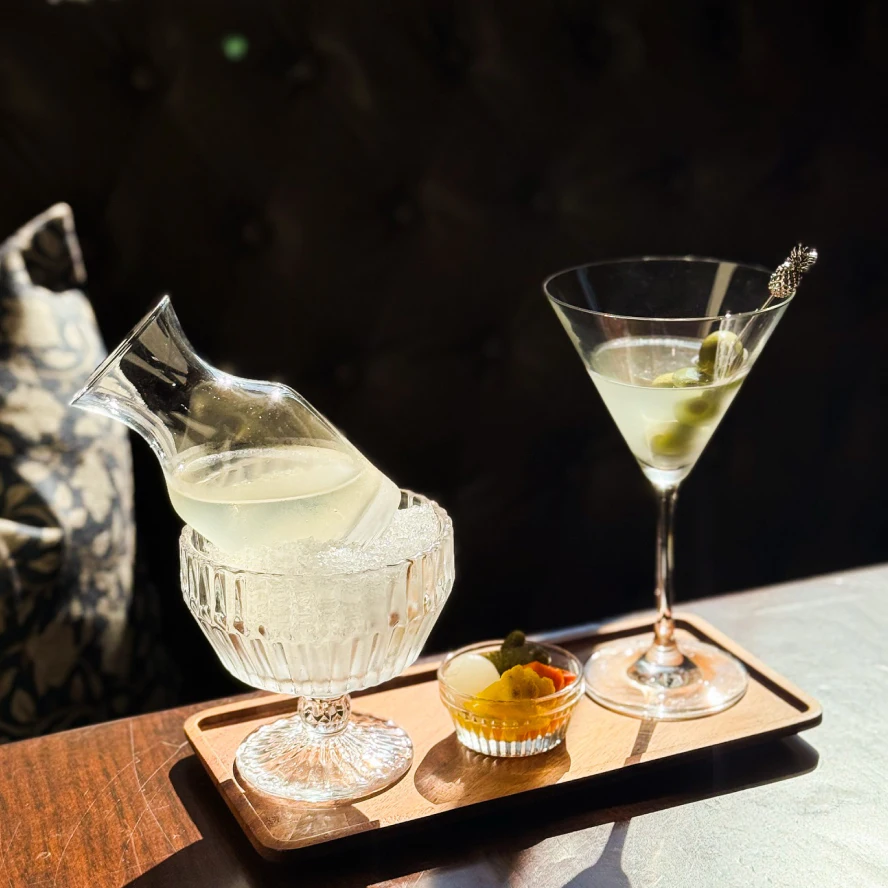 Different trendy cocktails sitting on a wood table in a modern upscale bar setting