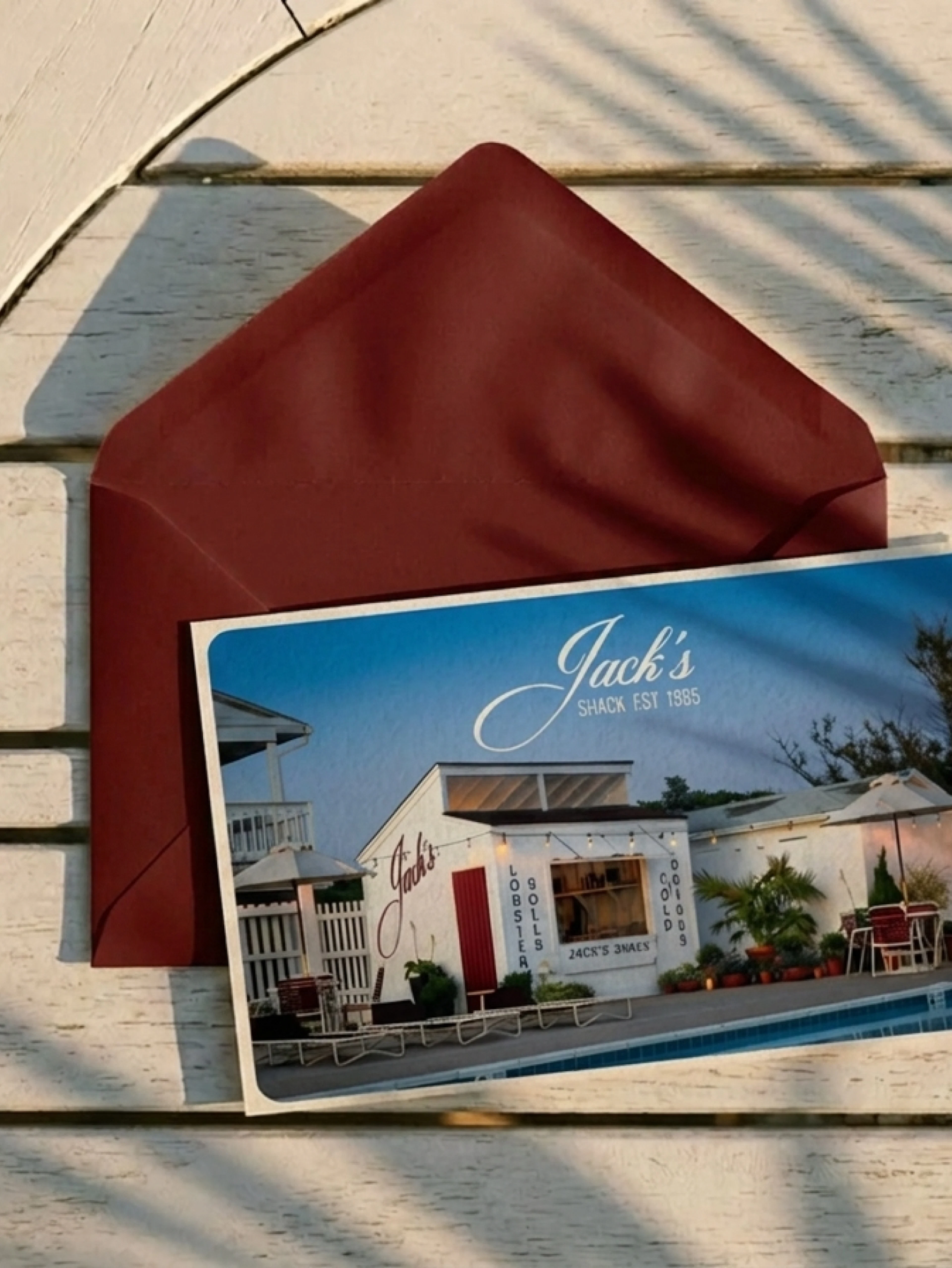 Jack's Shack postcard and red envelope on white wood