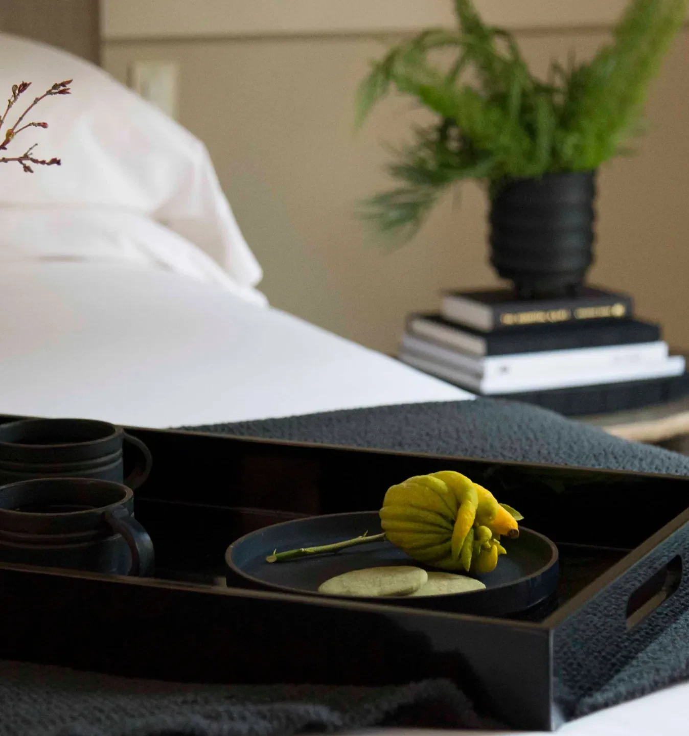Black tray with yellow flower and stones on a hotel bed