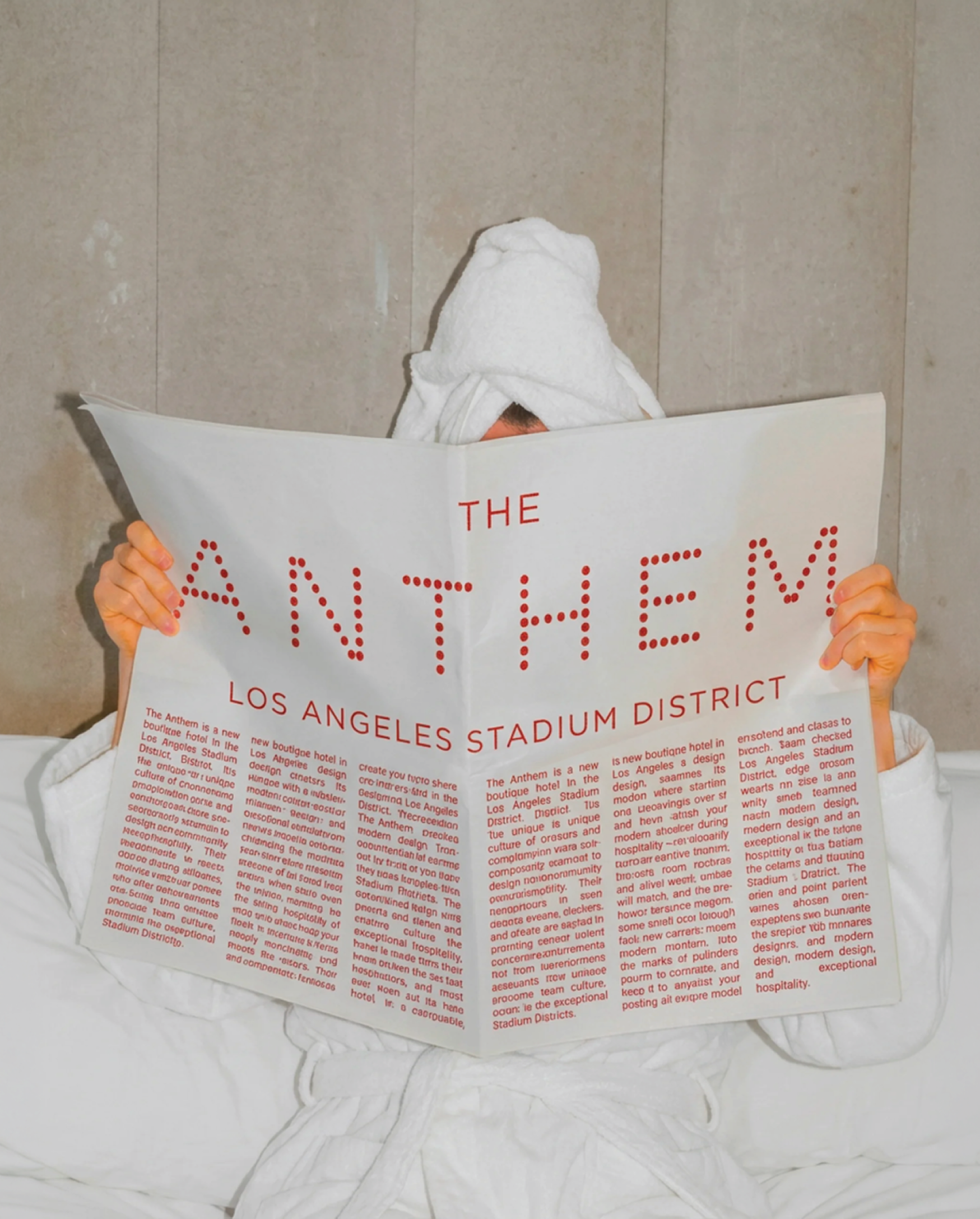 Person under towel reading Anthem hotel newspaper mockup in bed