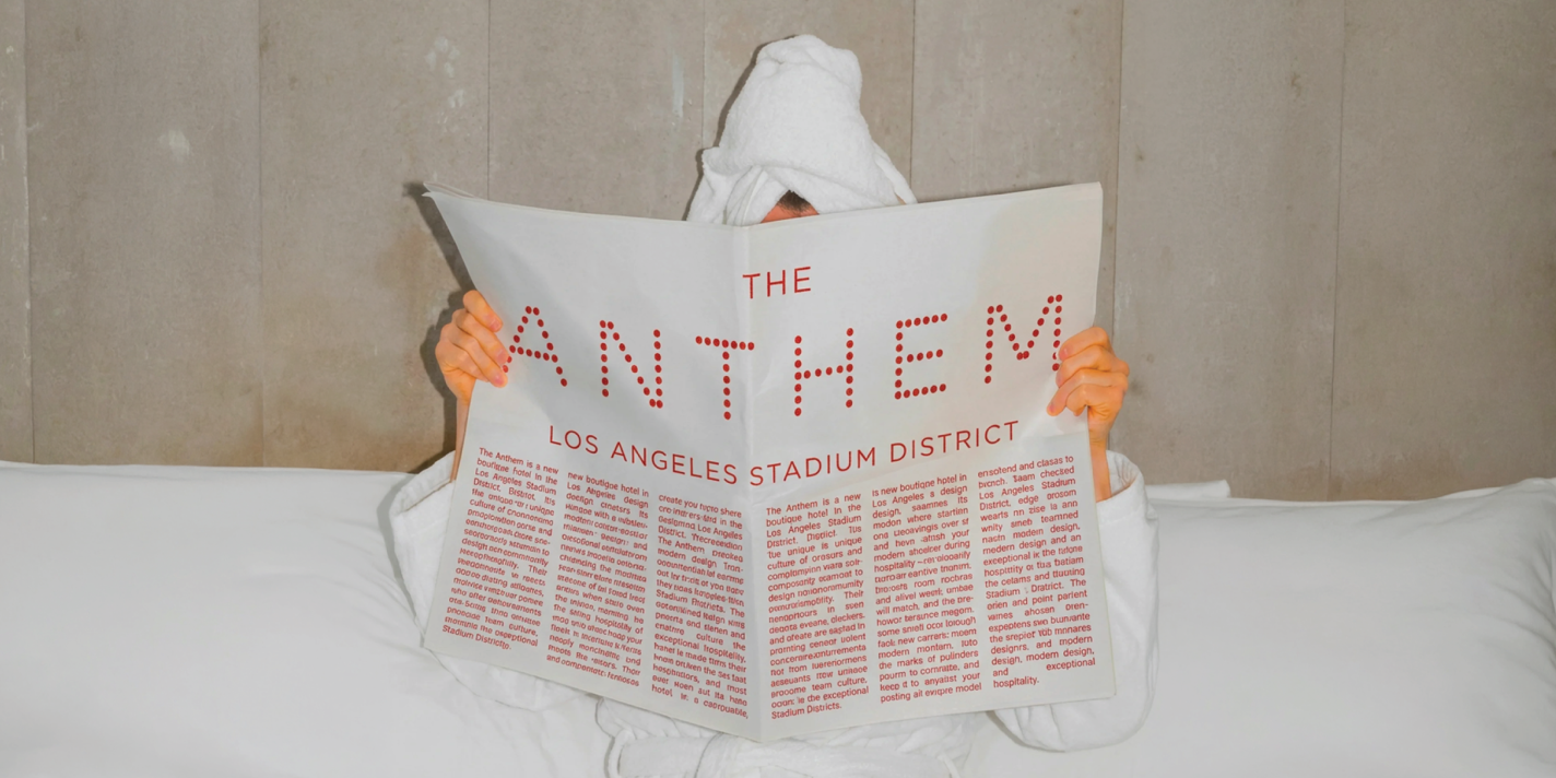 Person under towel reading Anthem hotel newspaper mockup in bed