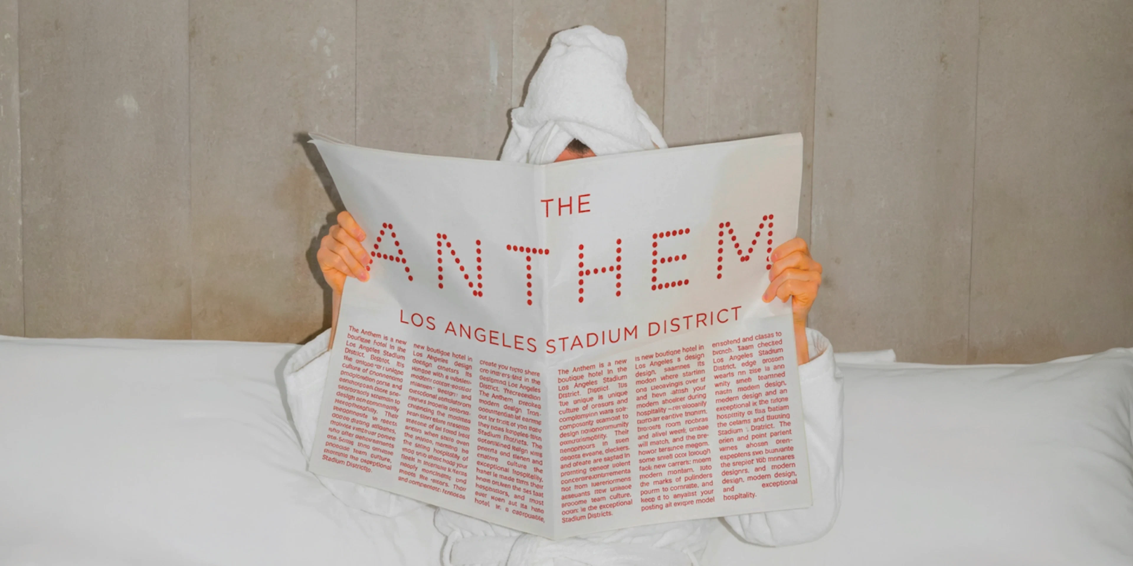 Person under towel reading Anthem hotel newspaper mockup in bed