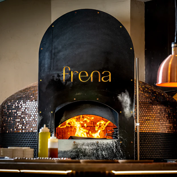 Frena wordmark on a black wood-fired oven with flames inside