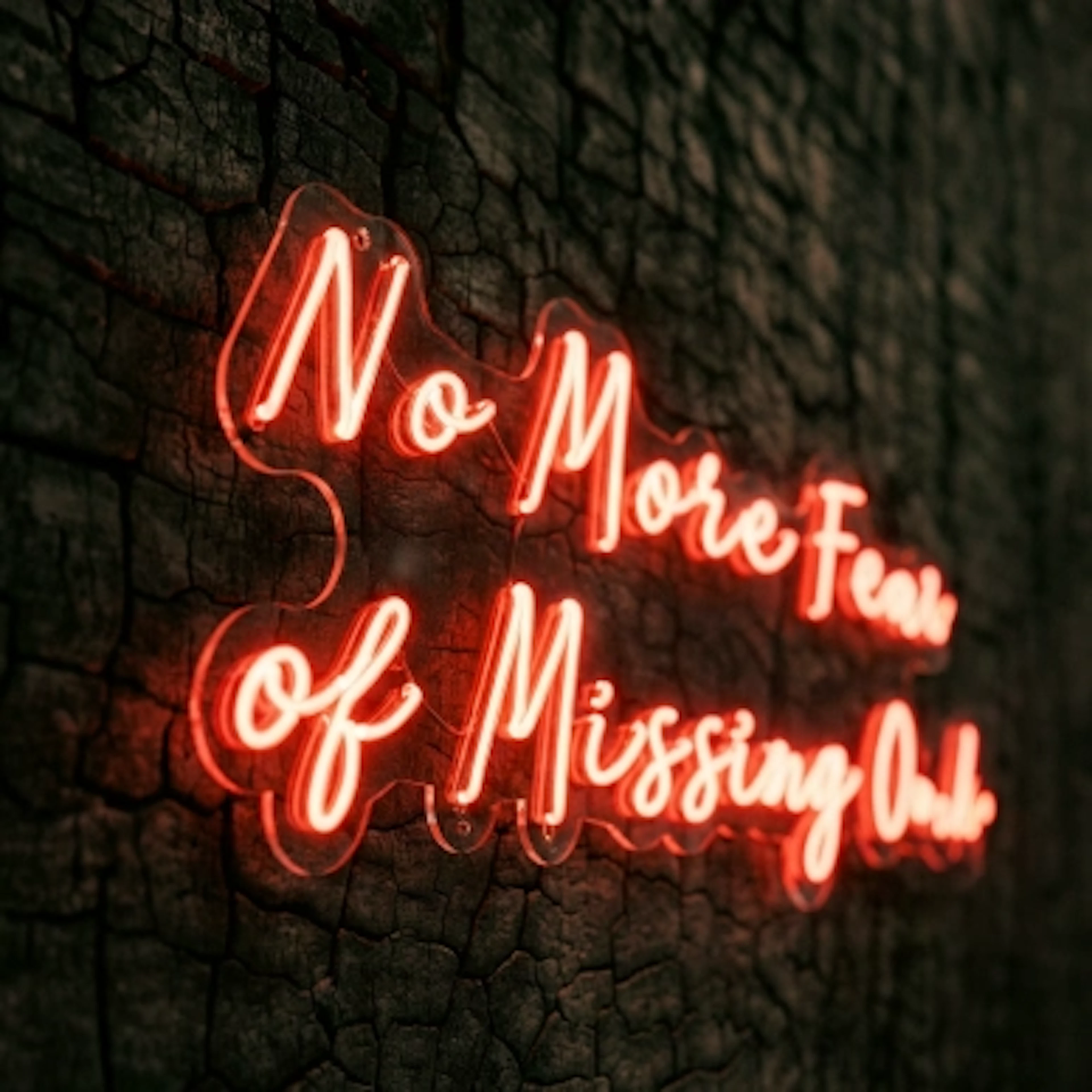 Neon sign reading No More Fear of Missing Out on charred wood