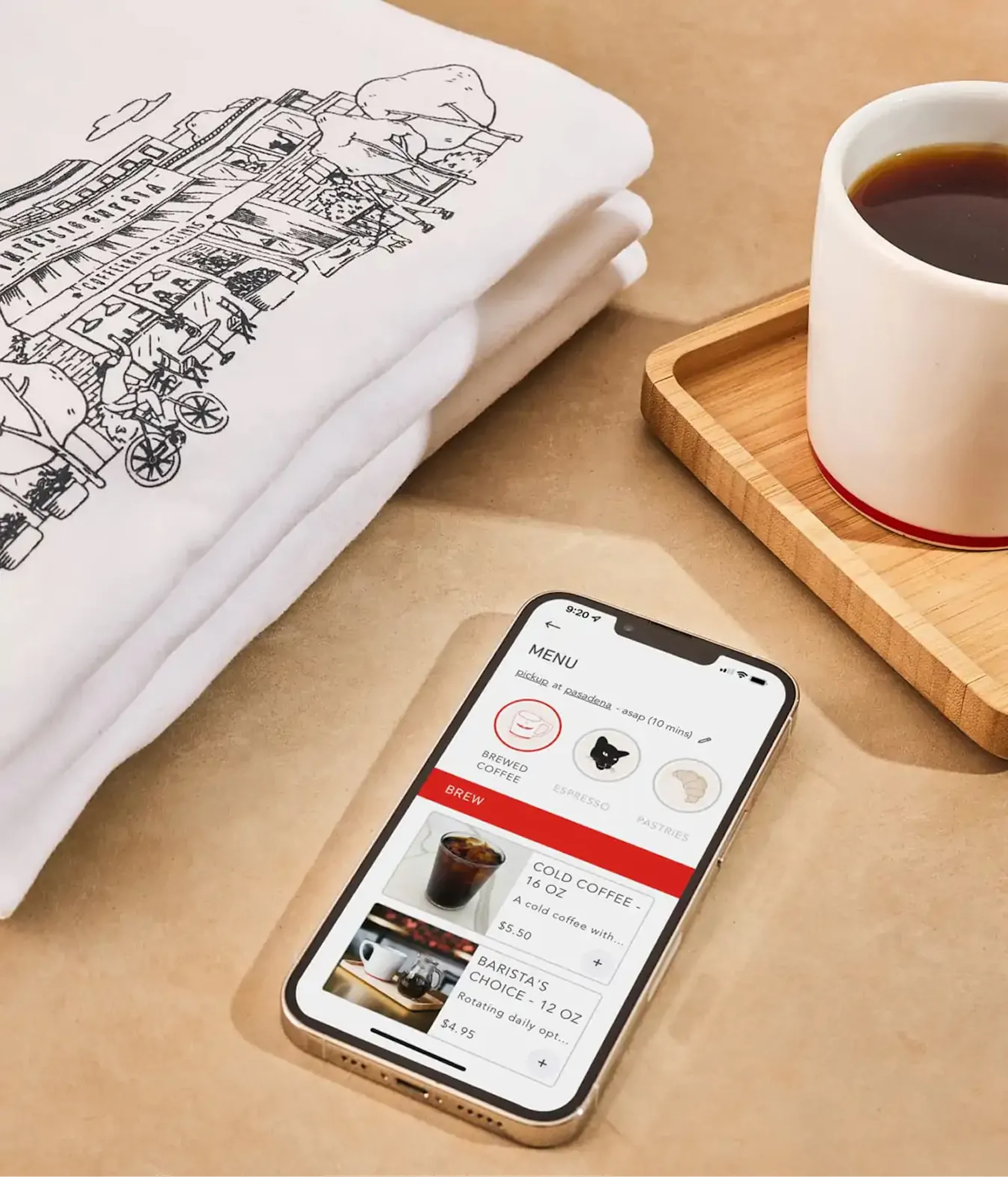 Folded t-shirt, coffee mug and phone showing a menu app