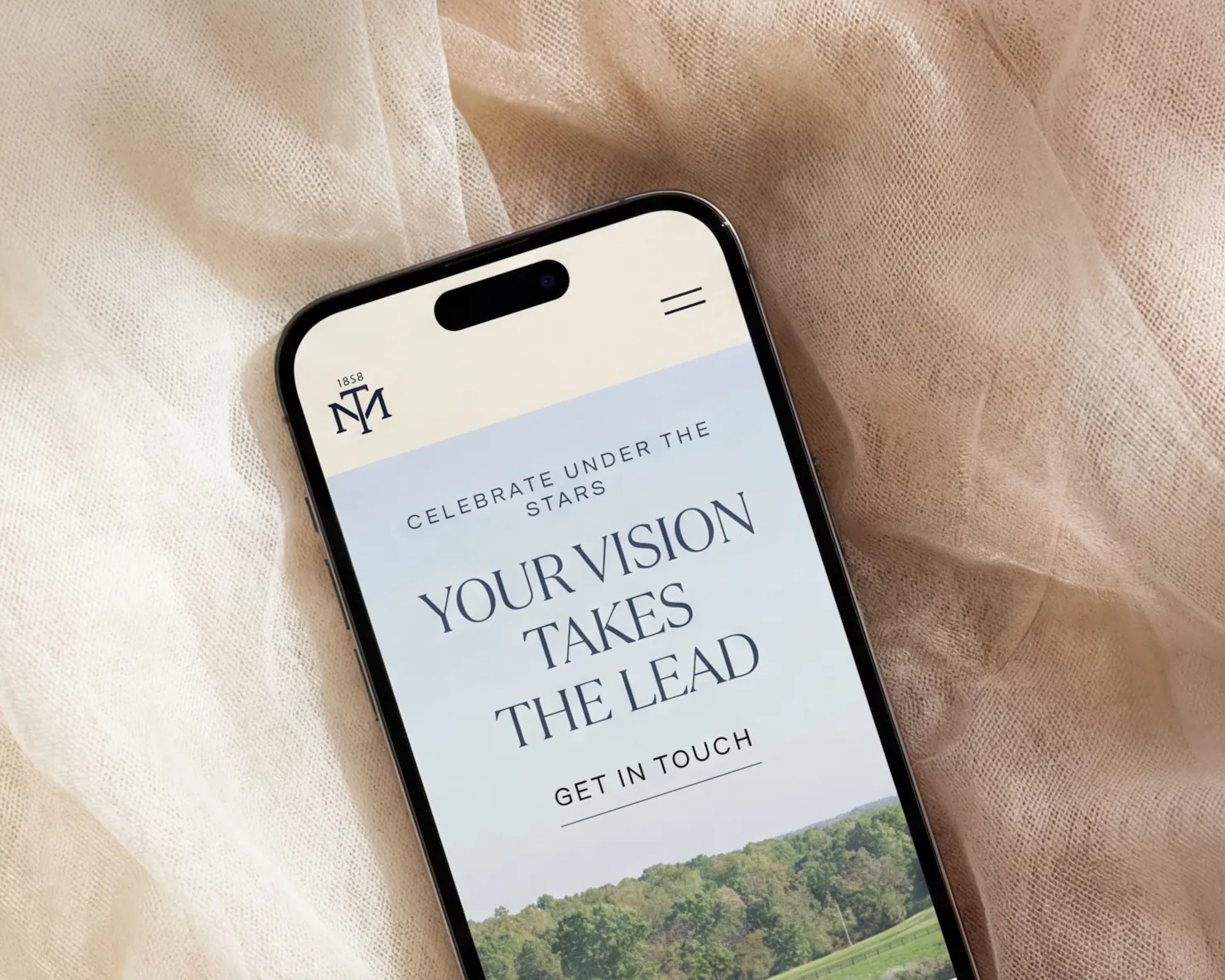 Phone displaying a wedding venue website homepage on draped fabric