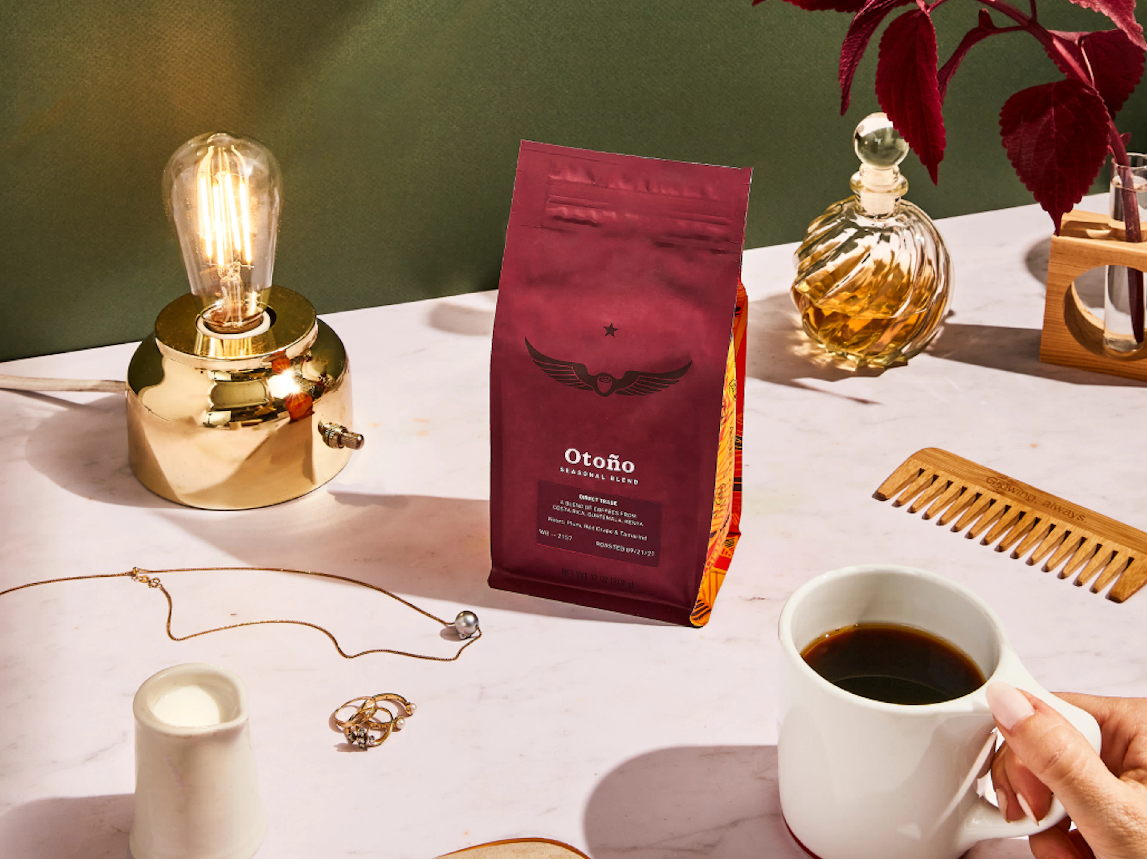 Bag of Otoño coffee beans on a table with a lamp and jewelry