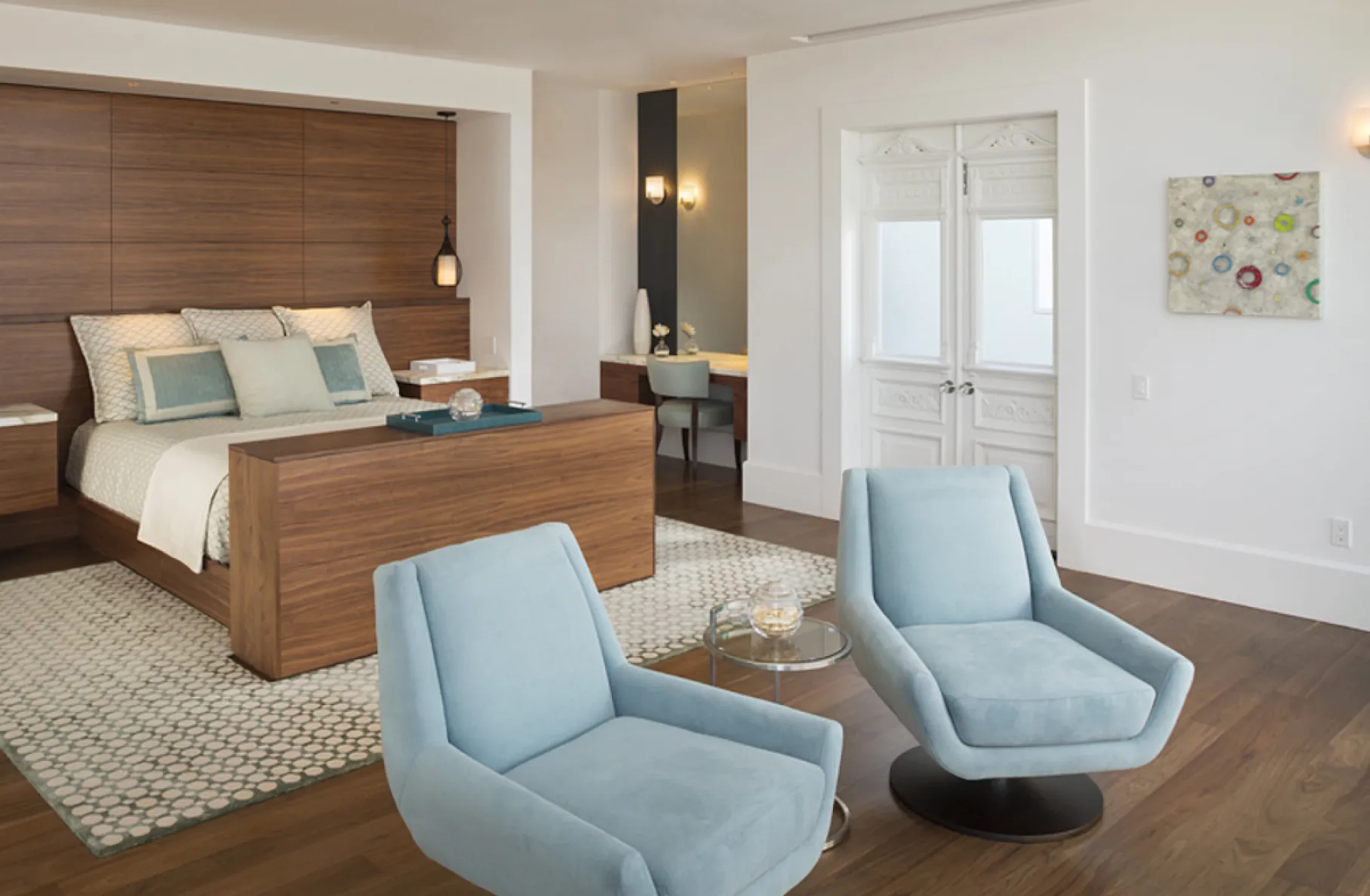Bedroom with wood headboard and two teal chairs