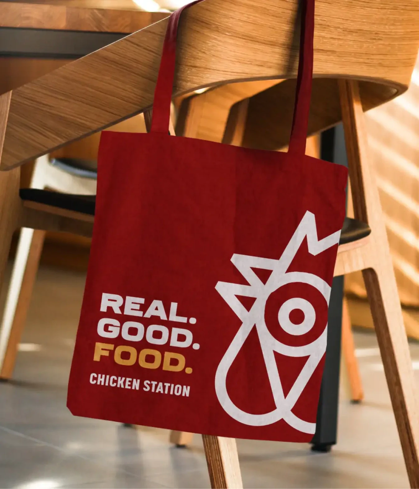 Red Chicken Station tote bag hanging on a wooden chair