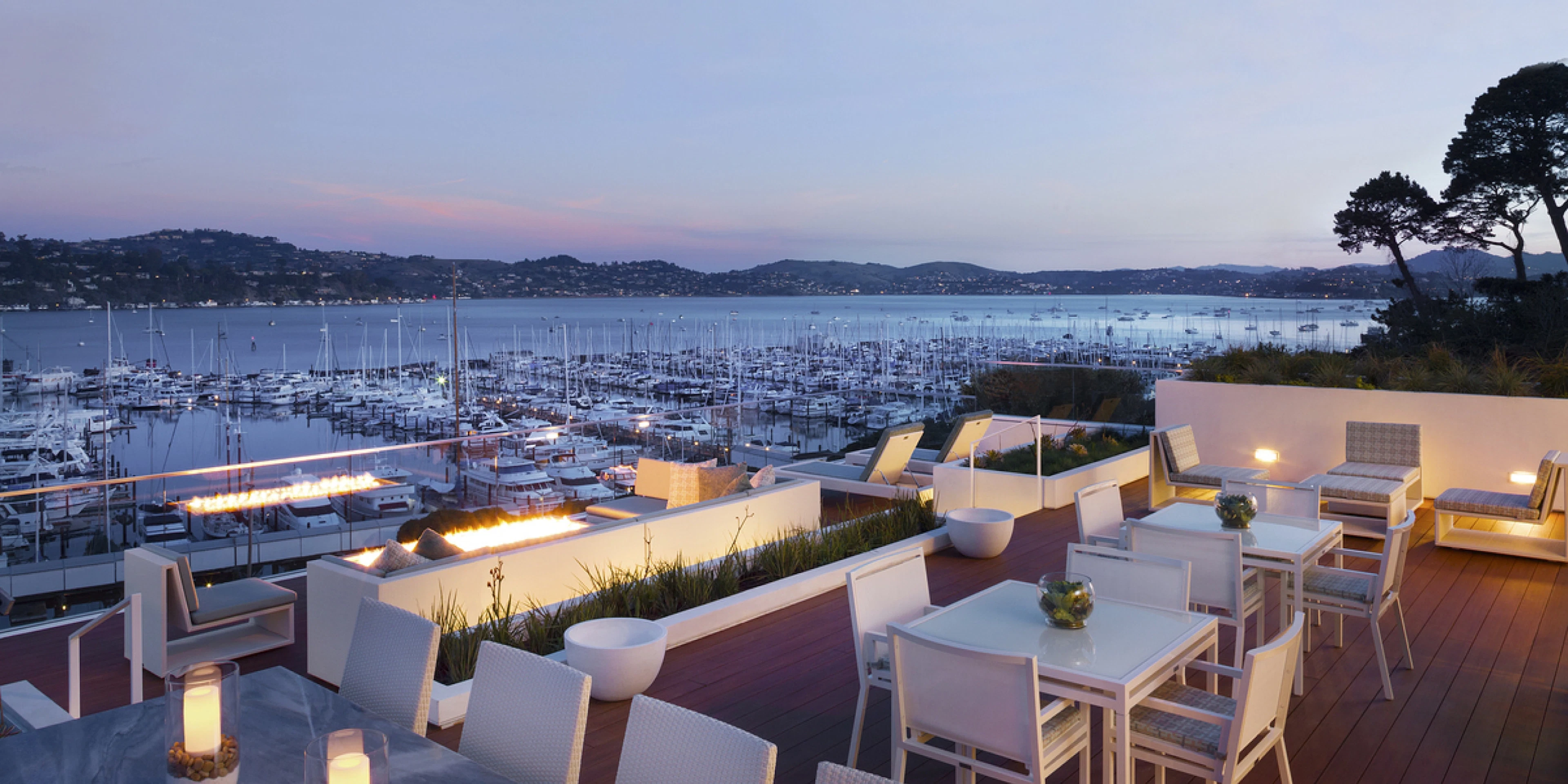 Rooftop lounge seating overlooking a marina at dusk