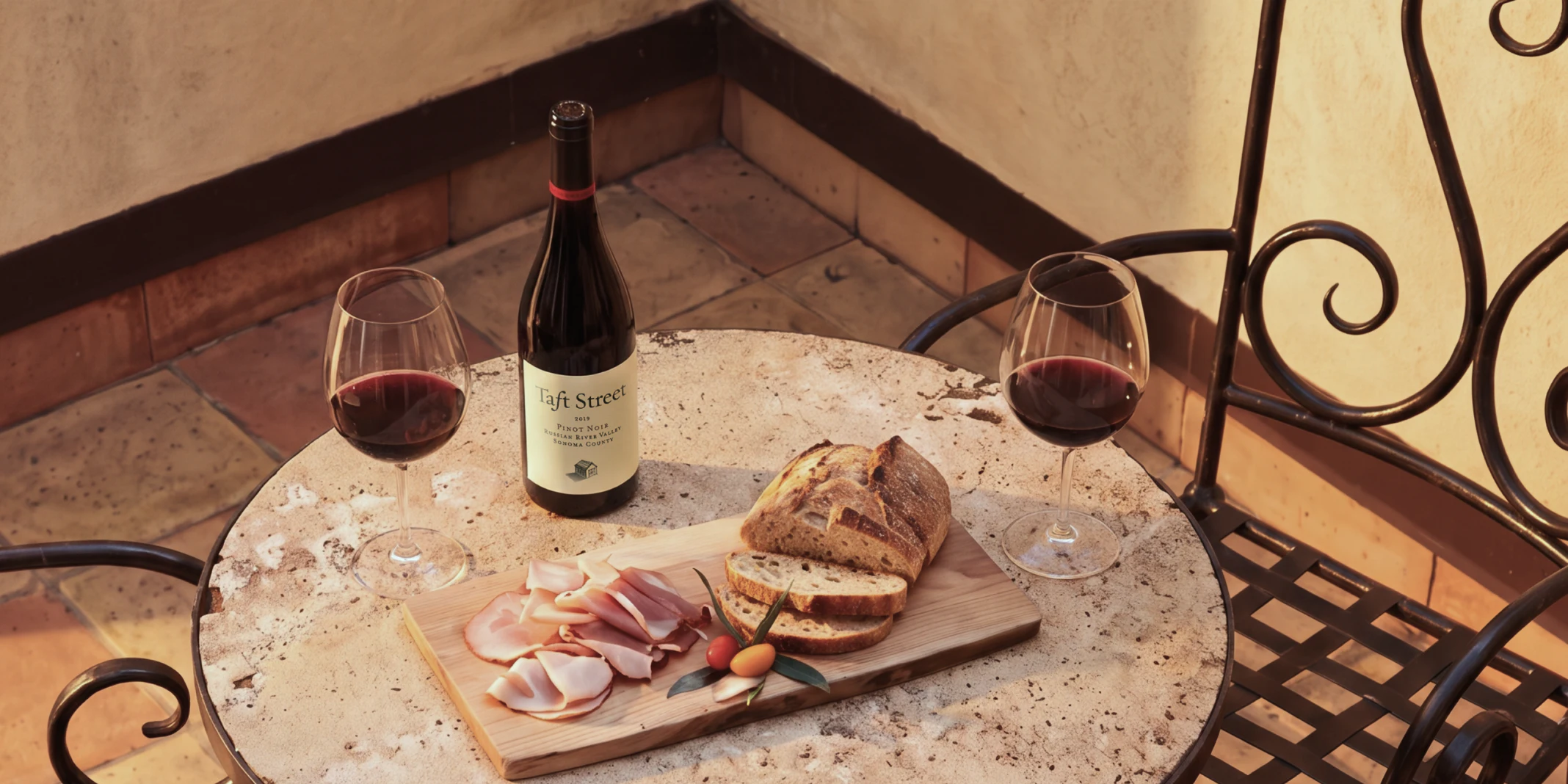 Wine bottle, glasses and bread board on outdoor table