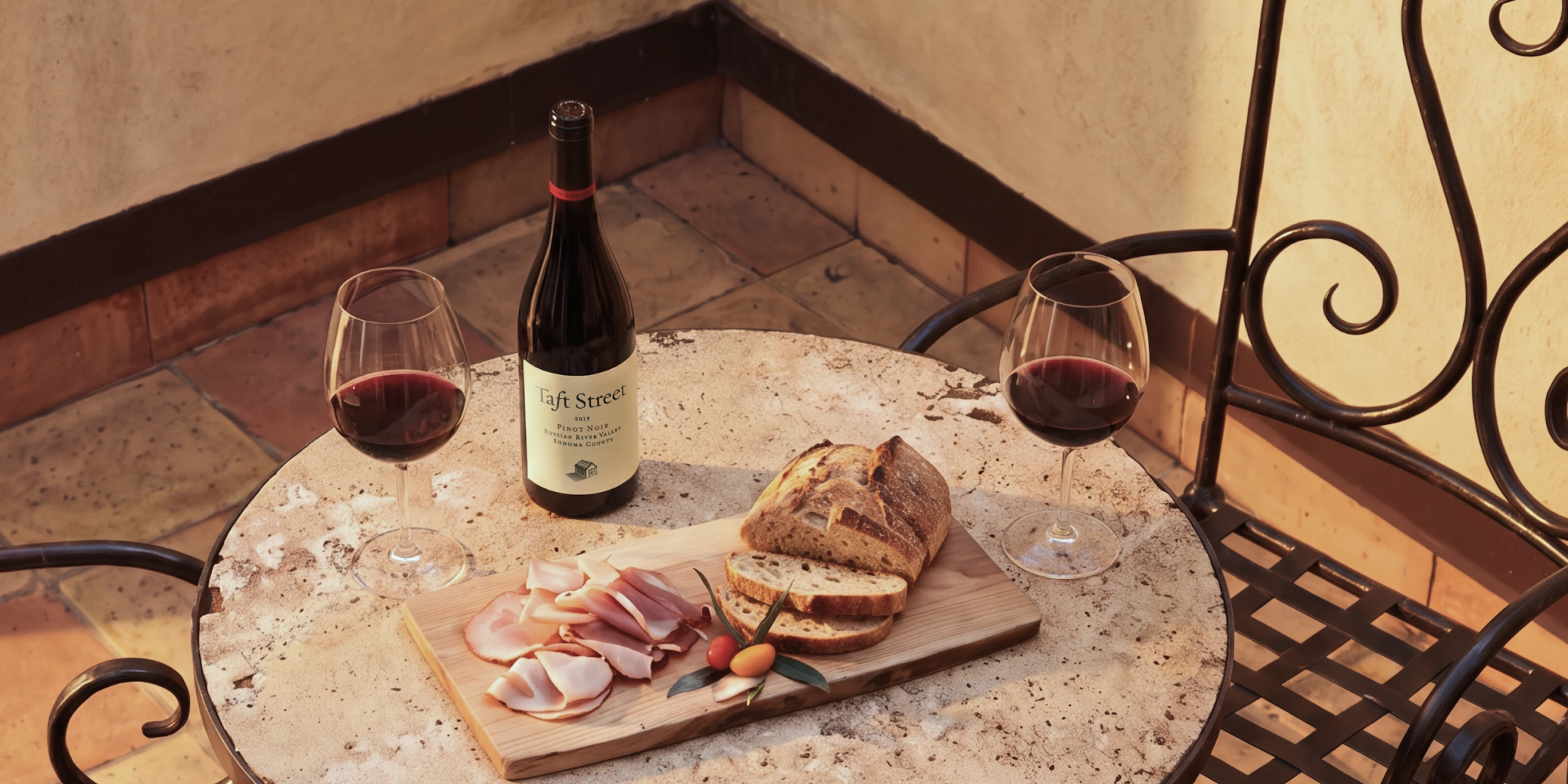 Wine bottle, glasses and bread board on outdoor table
