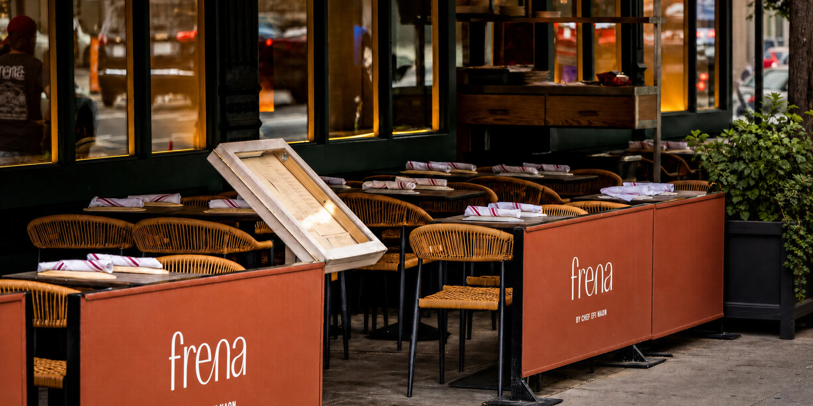 Frena sidewalk cafe seating with orange banners and rattan chairs