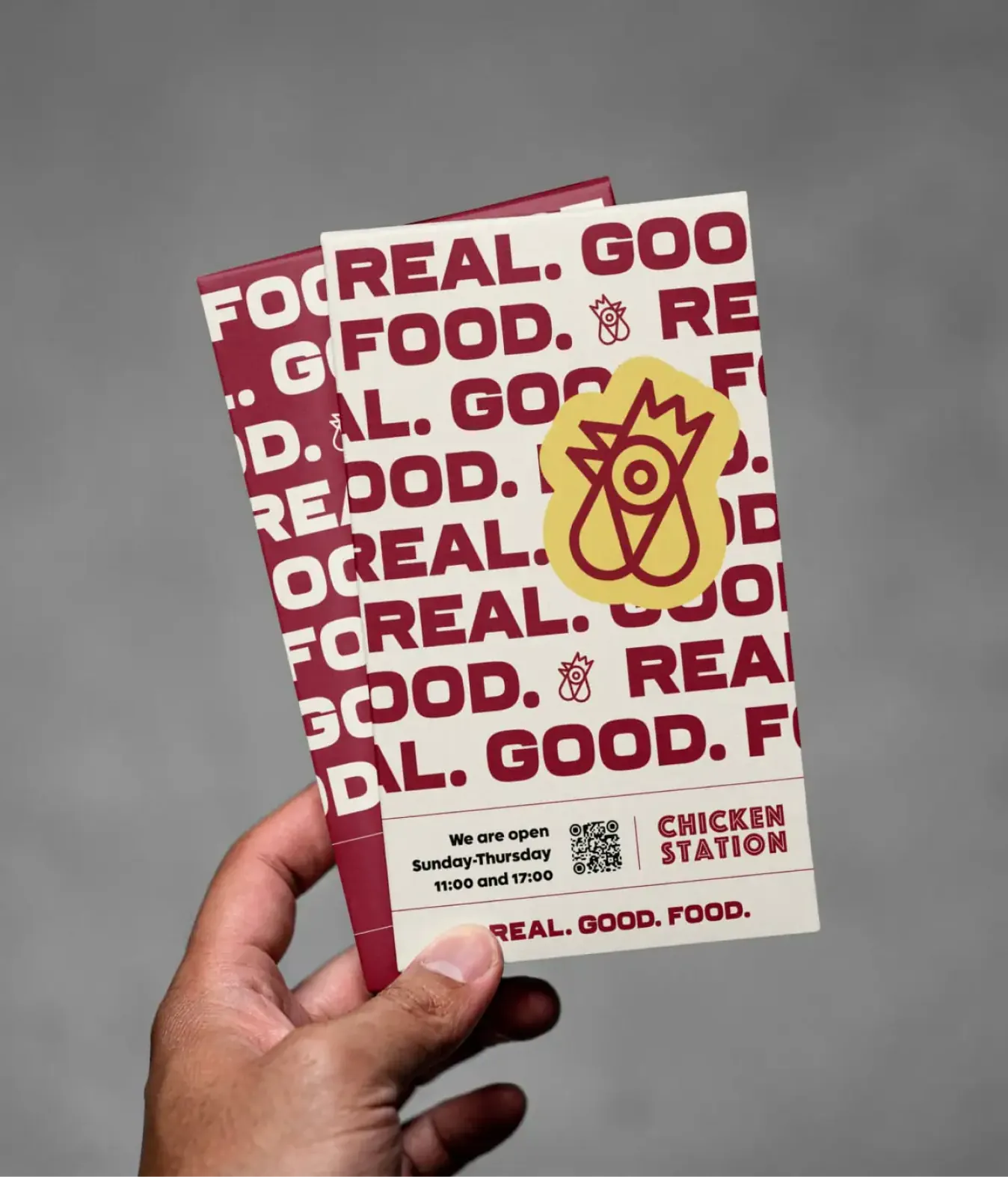 Hand holding Chicken Station brochures with repeated pattern