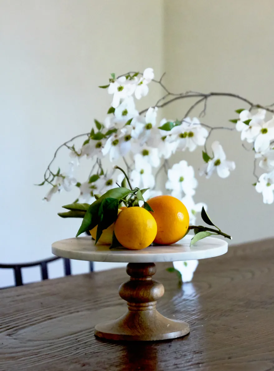 Oranges and white blossoms on a marble cake stand