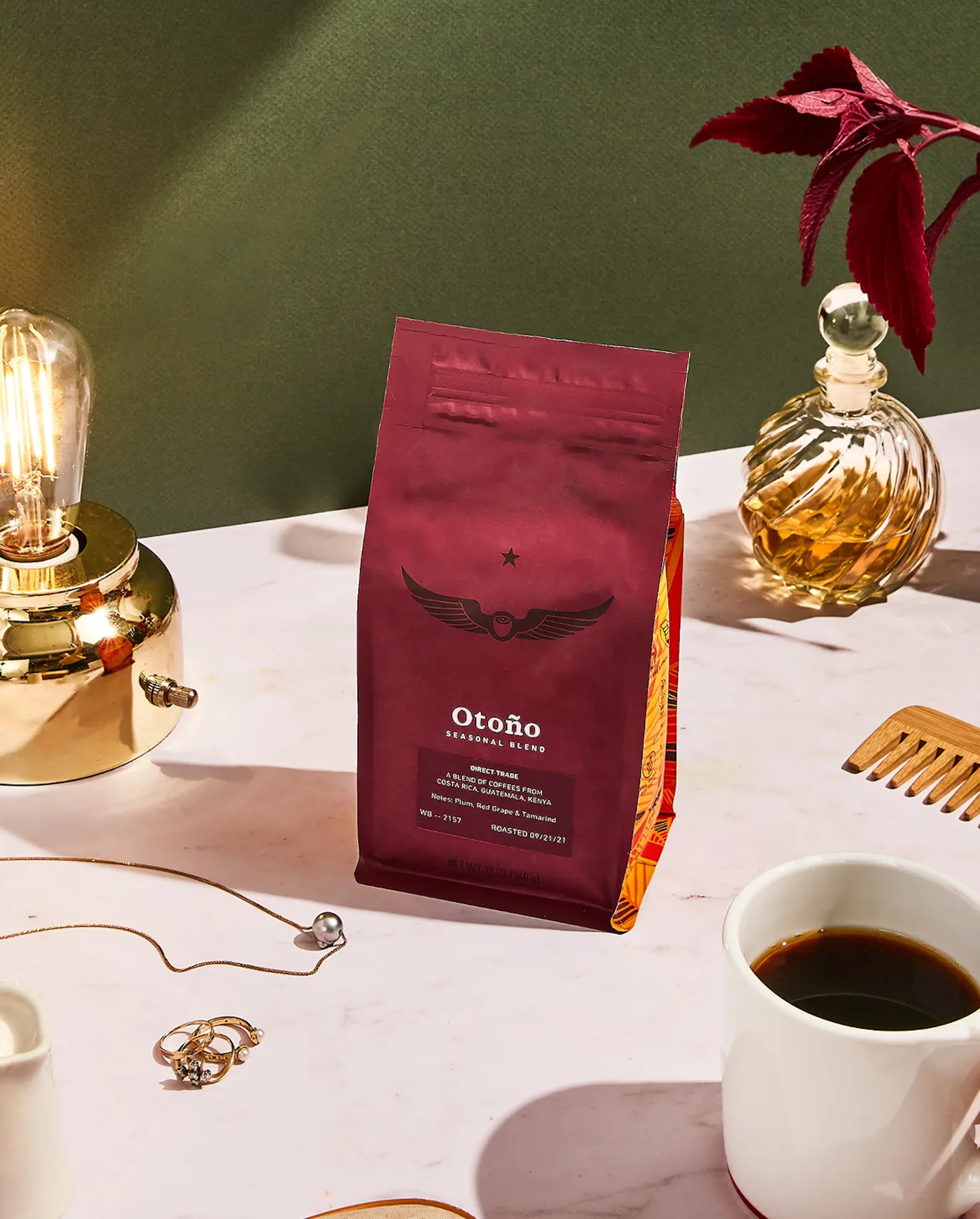 Bag of Otoño coffee beans on a table with a lamp and jewelry